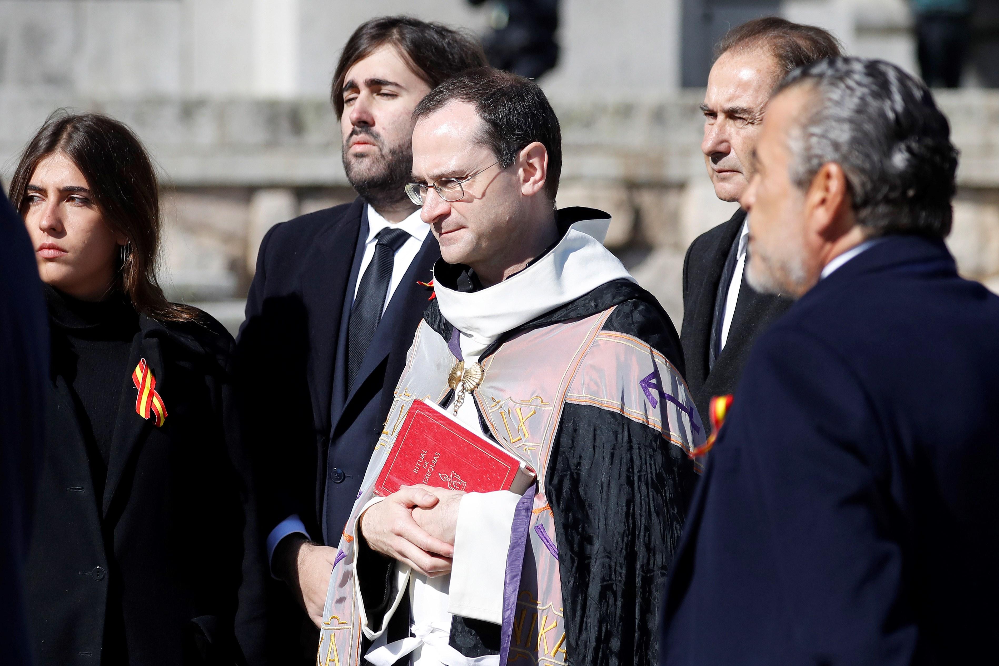 El prior de la Basílica Santiago Cantera (c) junto a los familiares de Francisco Franco tras introducir el féretro con los restos mortales del dictador en el coche fúnebre que lo llevará hasta el helicóptero encargado del traslado al cementerio de El Pard