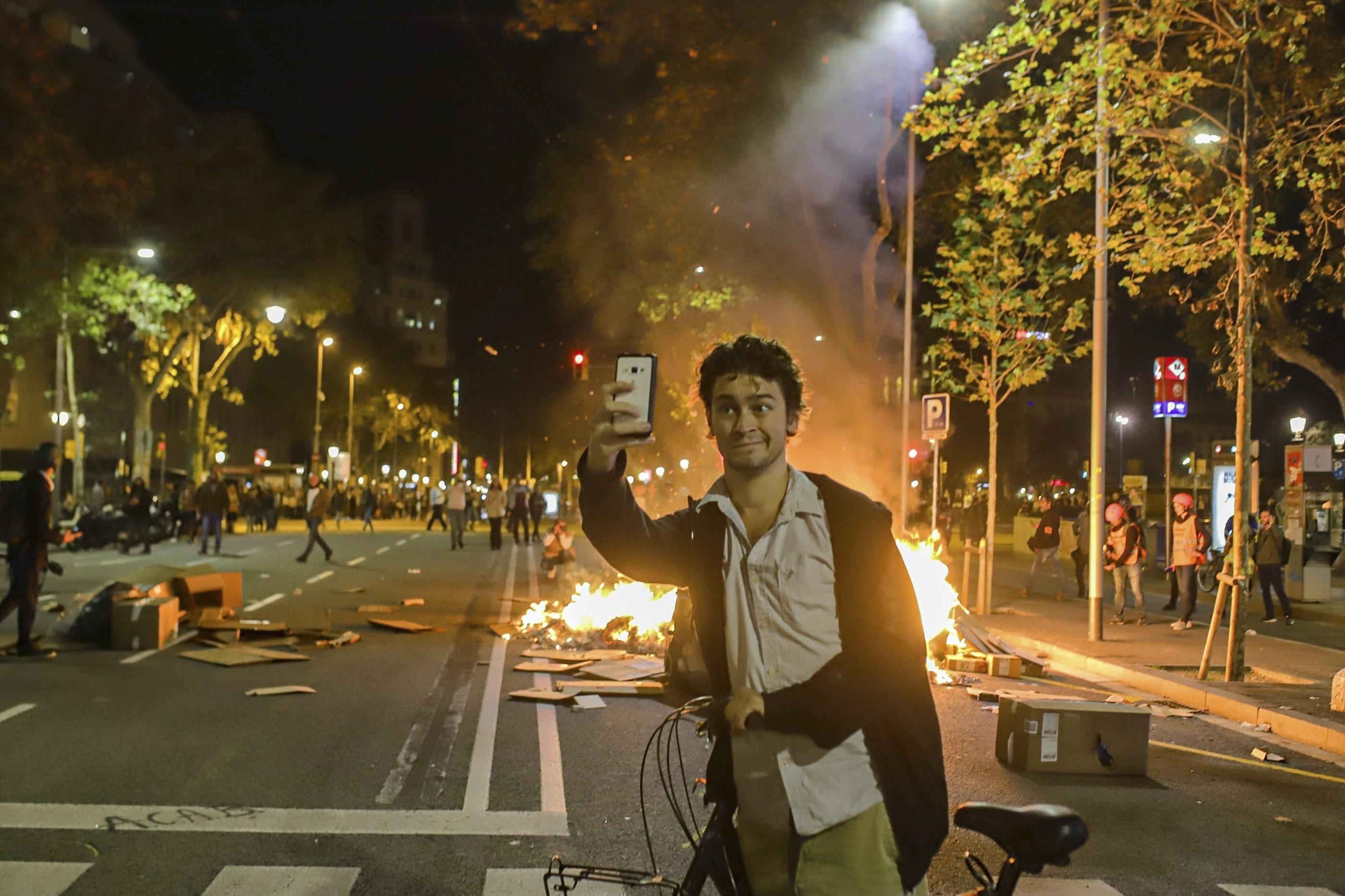 Un hombre se hace una foto durante los disturbios de Barcelona. 