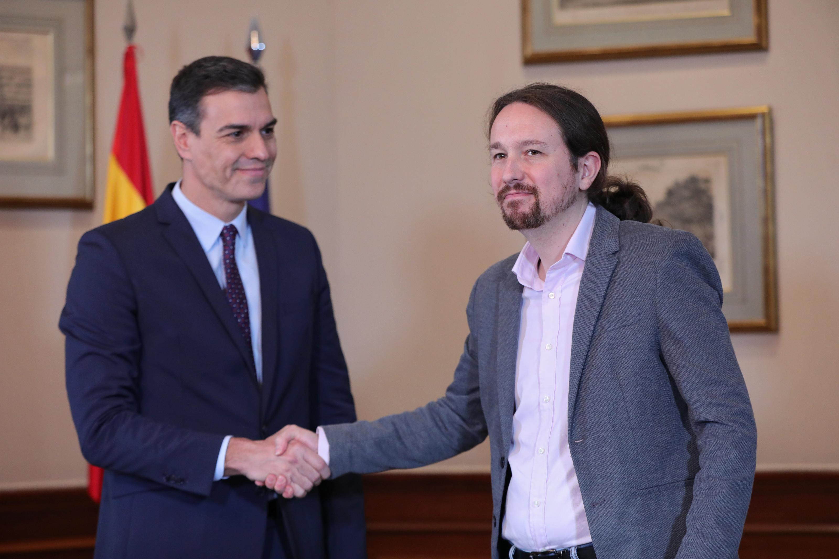 El presidente del Gobierno en funciones Pedro Sánchez y el líder de Podemos Pablo Iglesias se abrazan en el Congreso de los Diputados después de firmar el acuerdo de coalición.