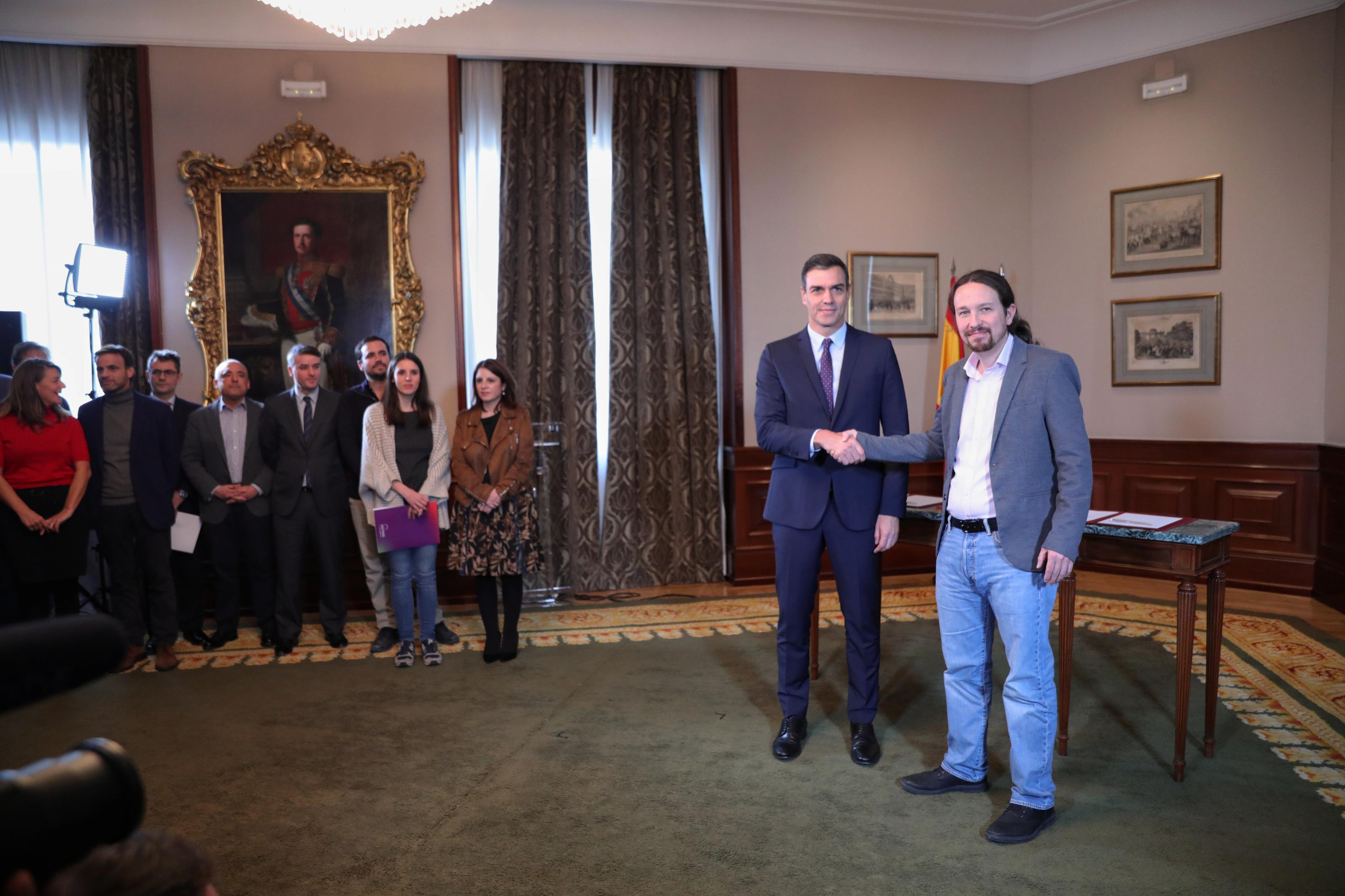 El presidente del Gobierno en funciones Pedro Sánchez y el líder de Podemos Pablo Iglesias se abrazan en el Congreso de los Diputados después de firmar el acuerdo de coalición.