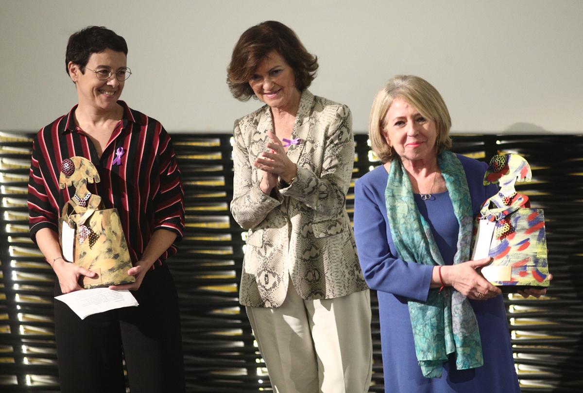 La vicepresidenta del Gobierno en funciones, Carmen Calvo (c), hace entrega del premio de reconocimiento a la periodistas, Alicia Gómez Montano (d) y Macarena Baena Garrido (i), durante el acto instittucional por el Día Contra la Violencia de Género en Ma