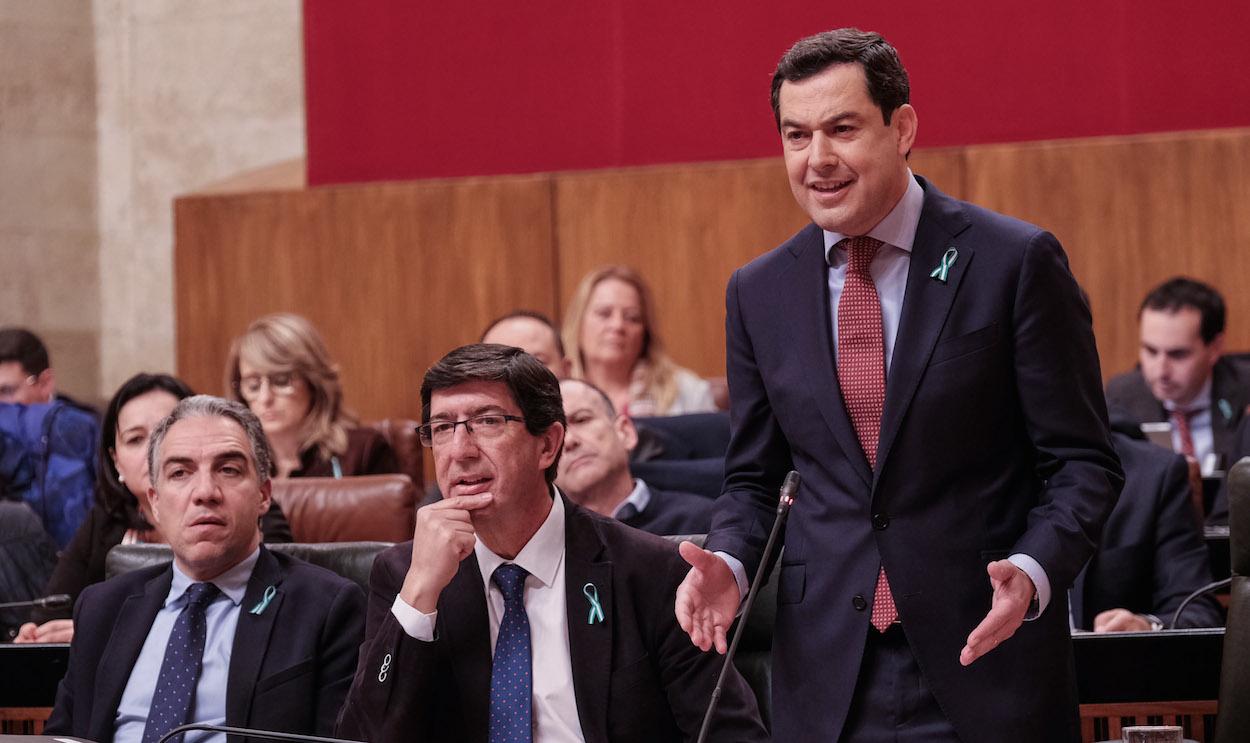 Juan Marín y Juanma Moreno exhiben en el Parlamento sus lazos blanquiverdes contra la ministra de Hacienda.
