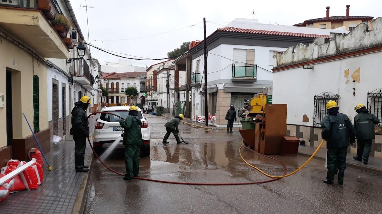 Efectivos de protección civil limpian las calles de Nerva anegadas por el temporal.