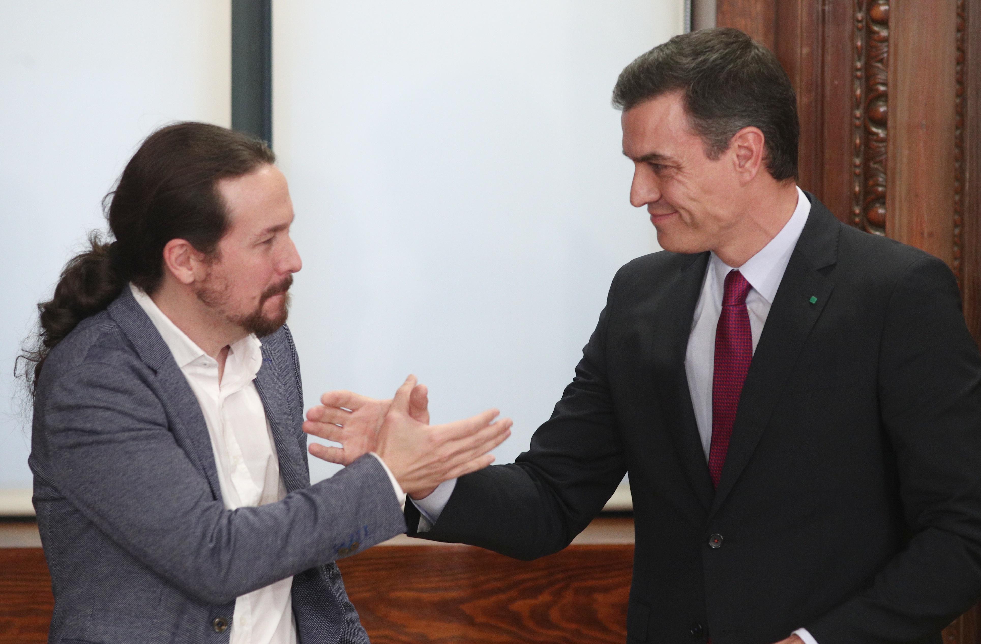 El presidente del Gobierno en funciones Pedro Sánchez (dech ) y el secretario general de Podemos Pablo Iglesias (izq) se dan la mano durante el acto de presentación del programa de Gobierno del 