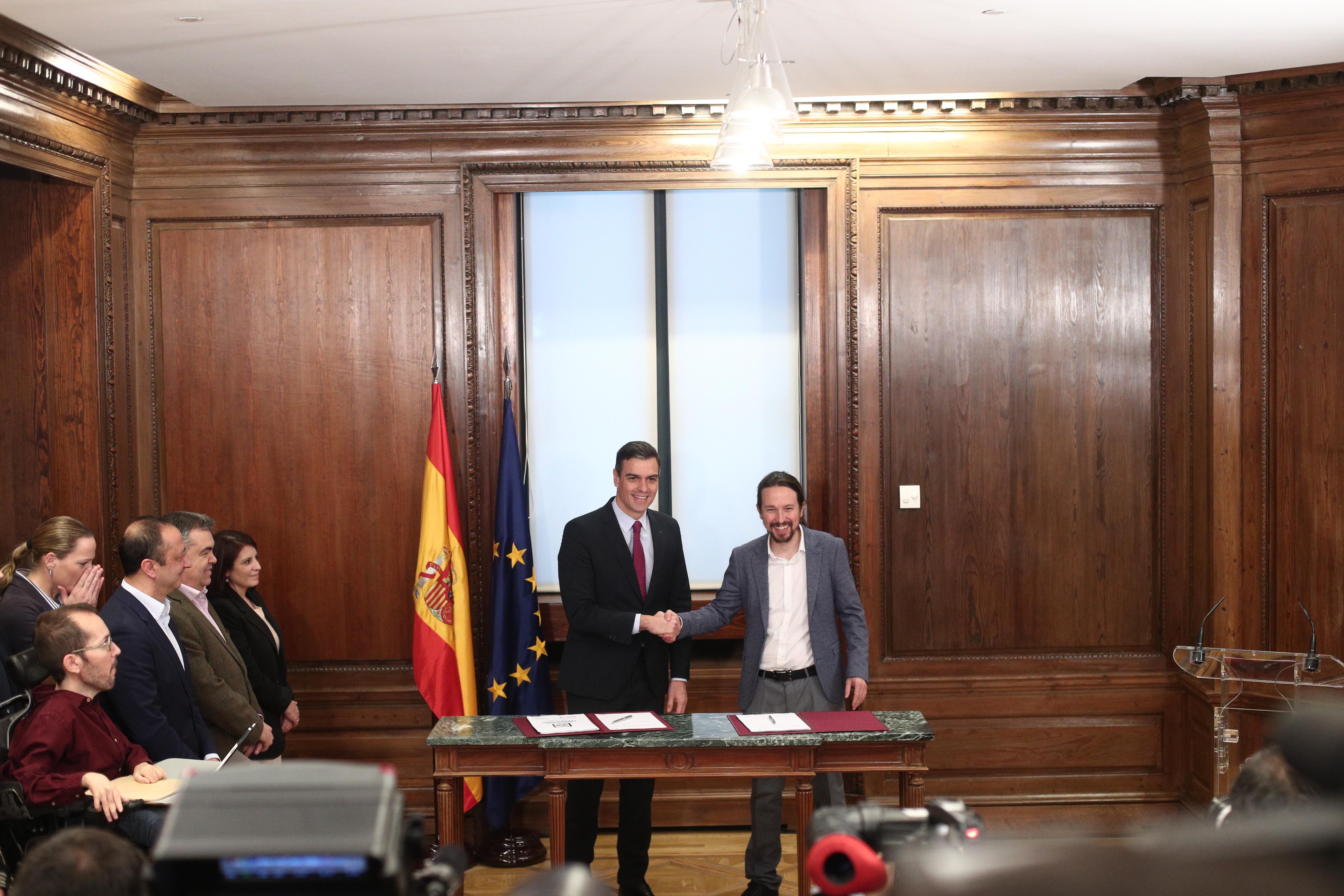 El presidente del Gobierno en funciones Pedro Sánchez y el secretario general de Podemos Pablo Iglesias se dan la mano durante el acto de presentación del programa de Gobierno 