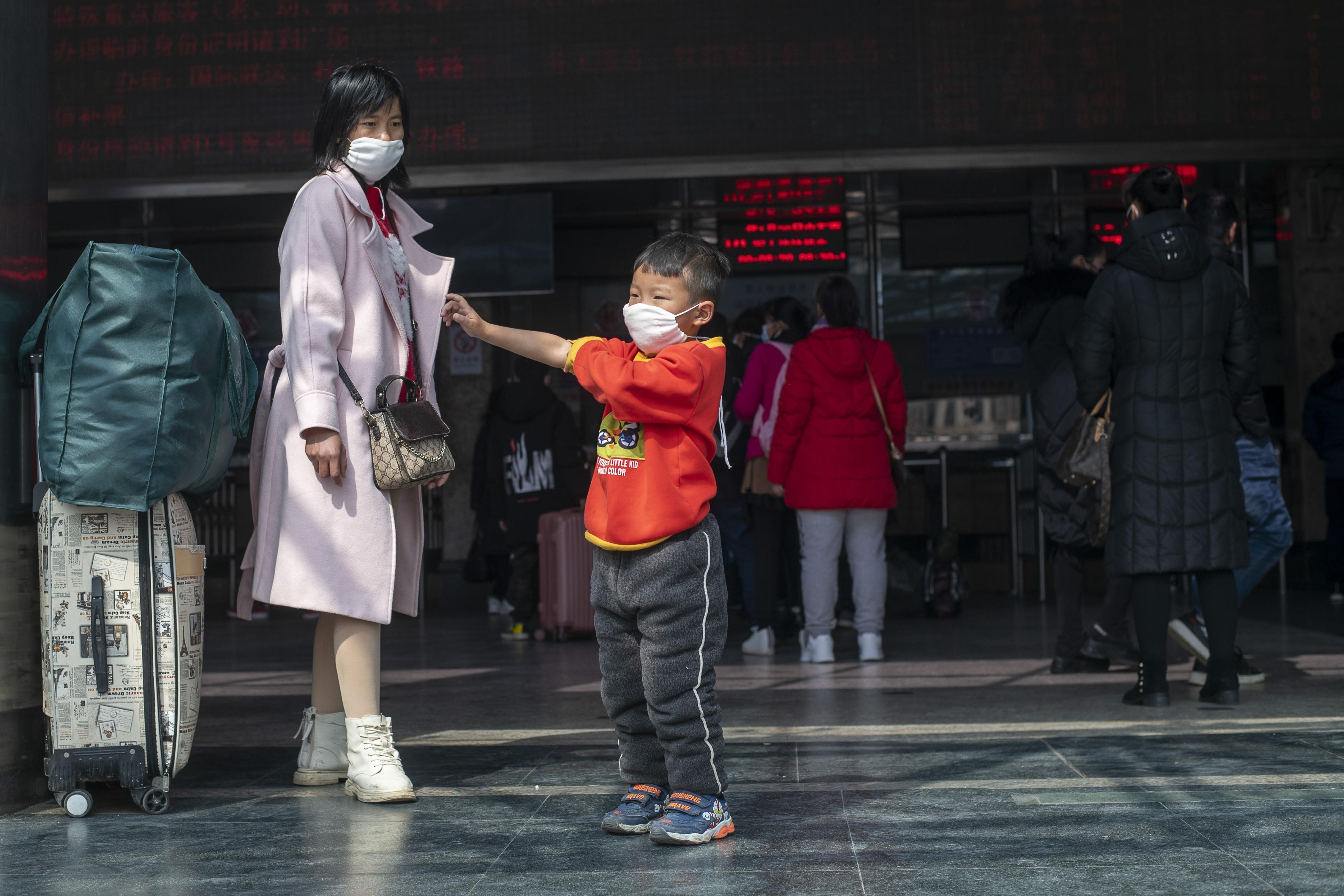 Una madre con su hijo en una estación de tren de China