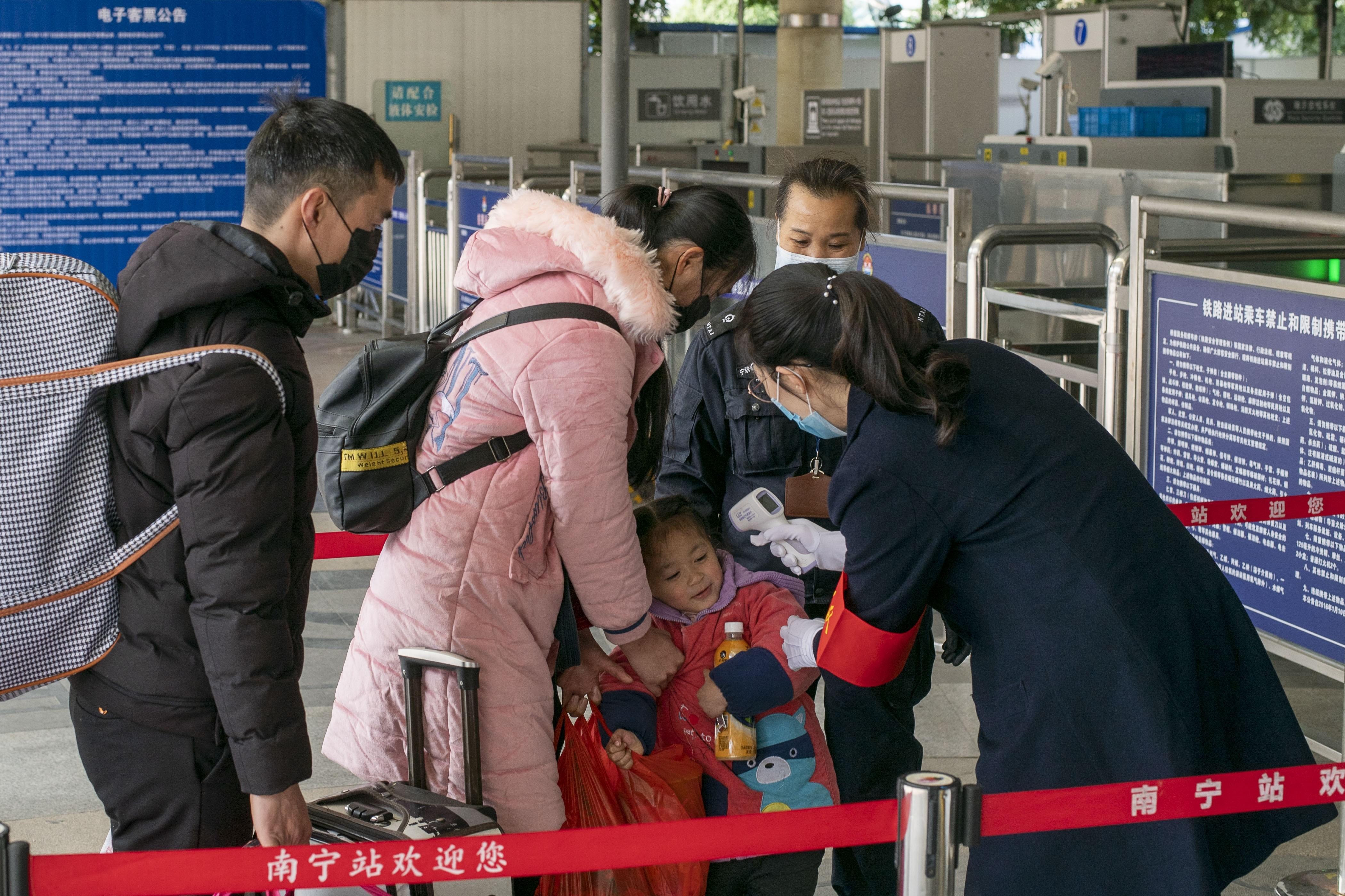 Una niña china se niega a que le tomen la temperatura para prevenir la expansión del coronavirus en la estación de tren de Nanning, China.