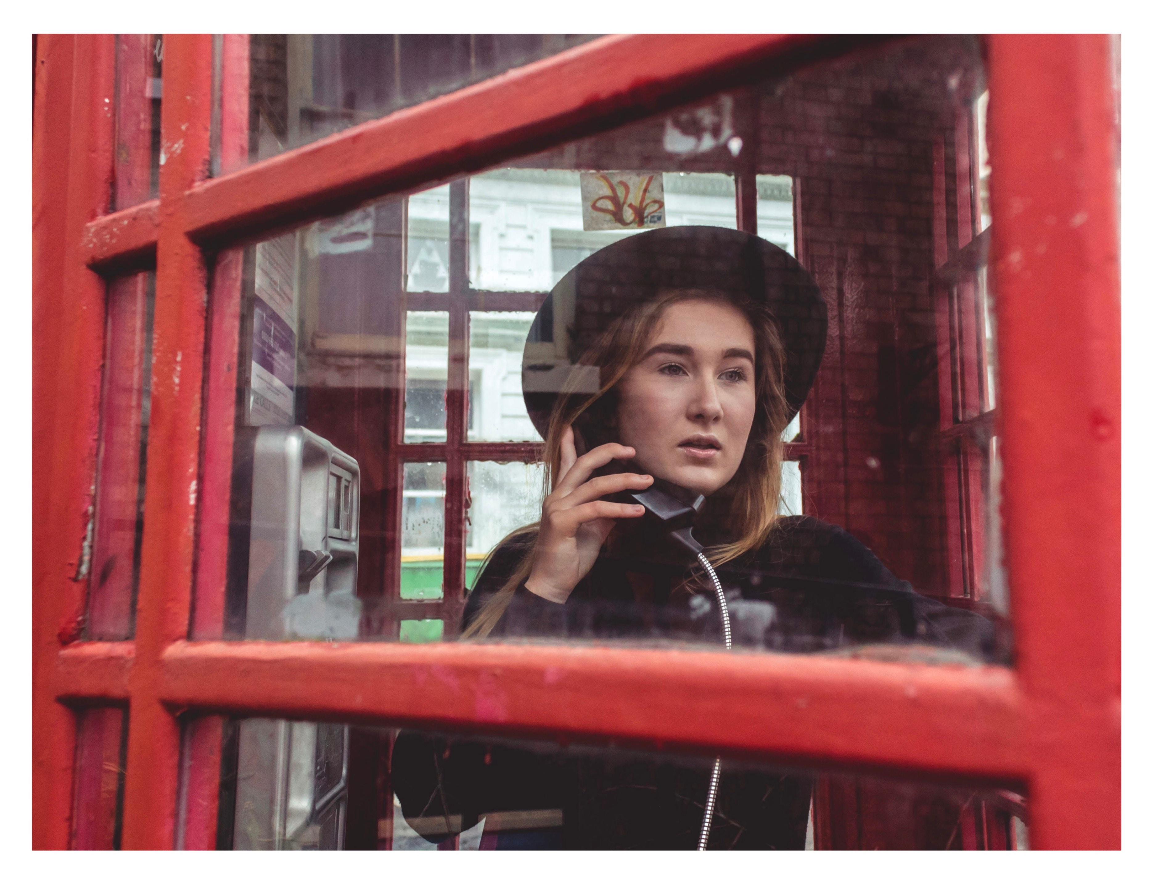Una mujer llama por teléfono en una típica cabina británica. Reeney Jenkins para Unsplash