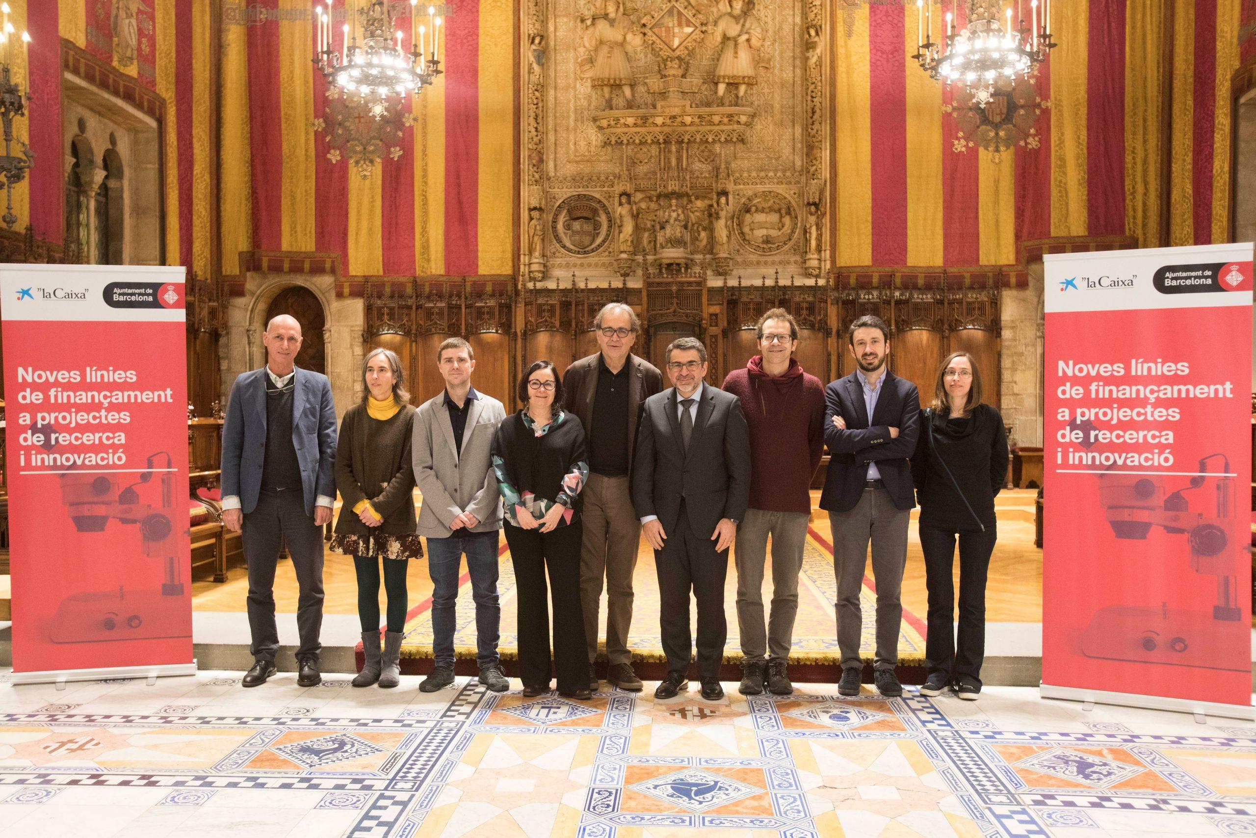 En el centro de la imagen, Joan Subirats, teniente de alcaldía de Cultura, Educación, Ciencia y Comunidad, y Àngel Font, director corporativo de Investigación y Estrategia de la Fundación ”la Caixa”, junto a siete investigadores líderes de los proyectos p