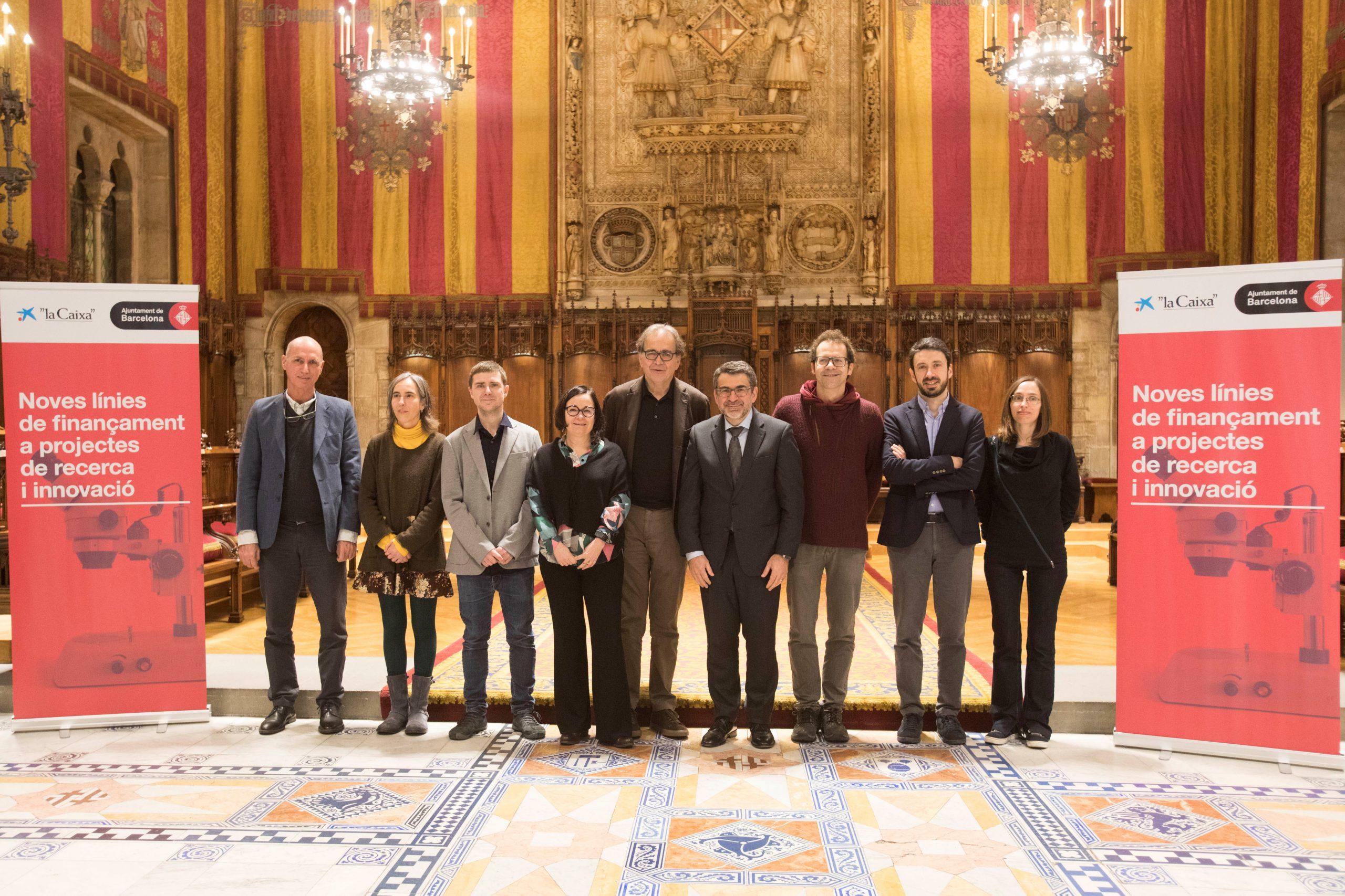 En el centro de la imagen, Joan Subirats, teniente de alcaldía de Cultura, Educación, Ciencia y Comunidad, y Àngel Font, director corporativo de Investigación y Estrategia de la Fundación ”la Caixa”, junto a siete investigadores líderes de los proyectos p