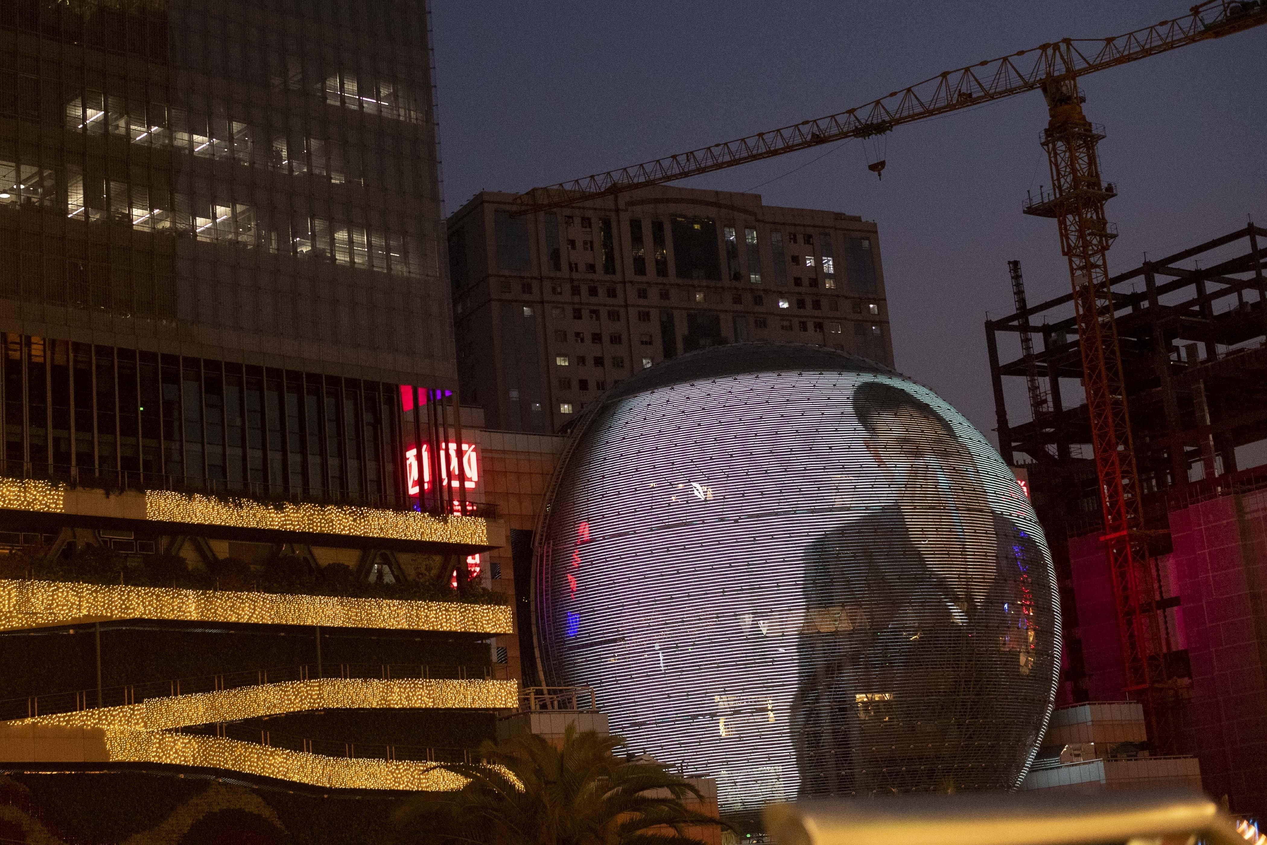 Una pantalla gigante muestra frente a un centro comercial cómo ponerse una mascarilla. EP