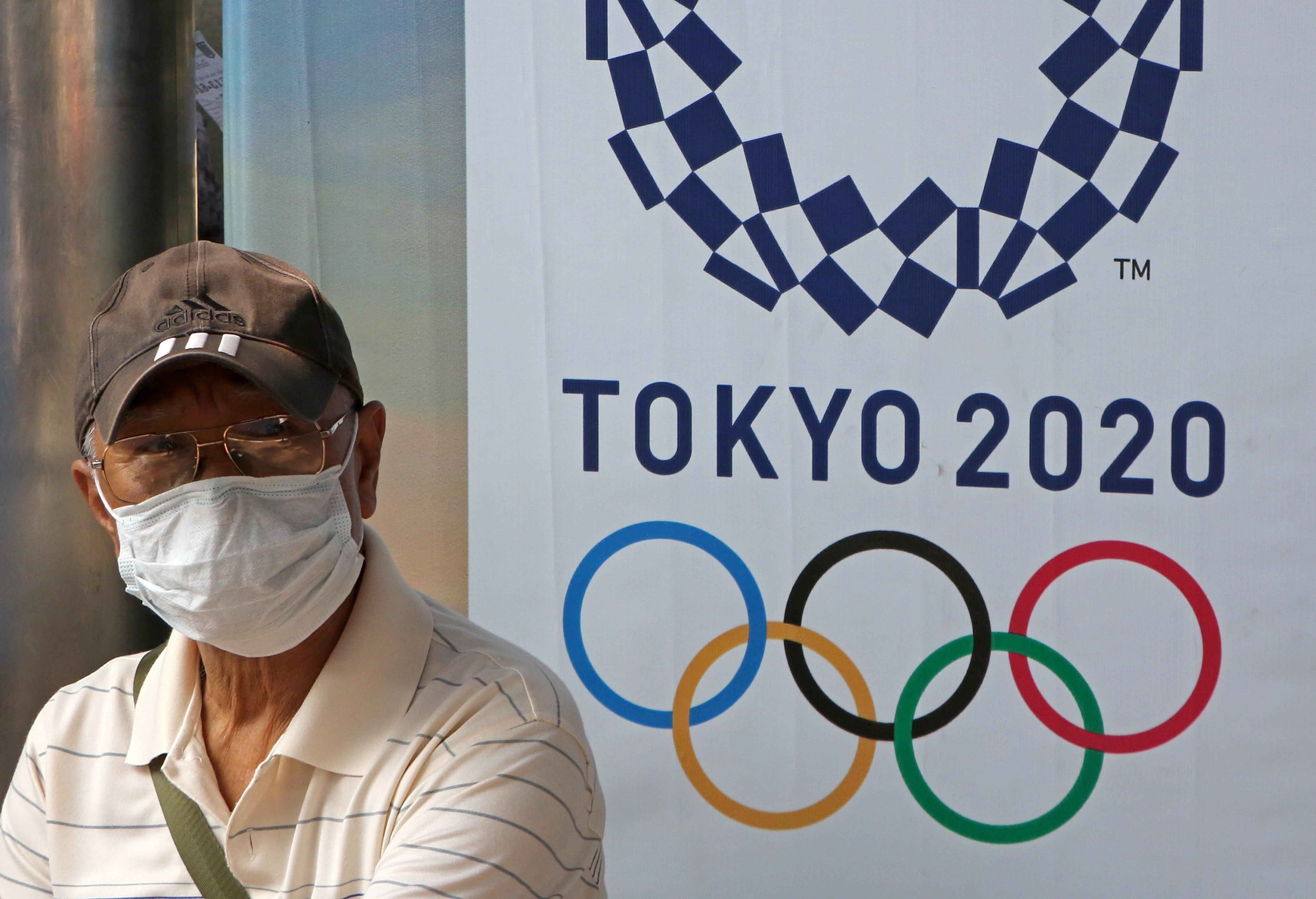 Un hombre lleva una mascarilla ante un cartel de Tokyo 2020