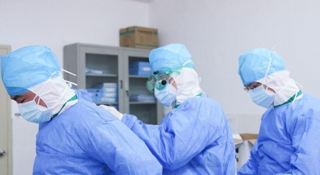 Médicos se ayudan mutuamente para ponerse trajes protectores contra el coronavirus en un vestuario / Europapress