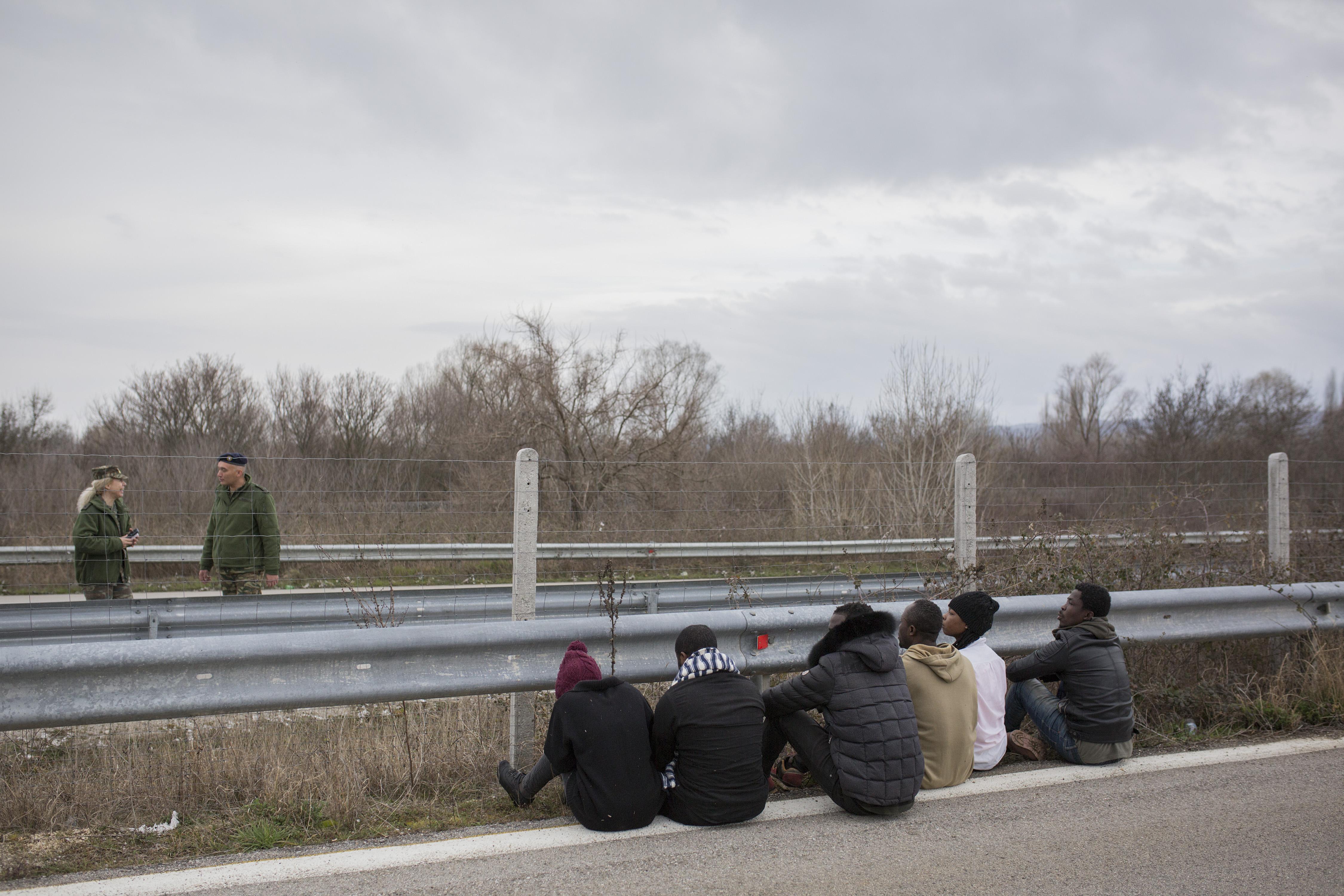 Migrantes en Grecia sentados en la calzada. EP