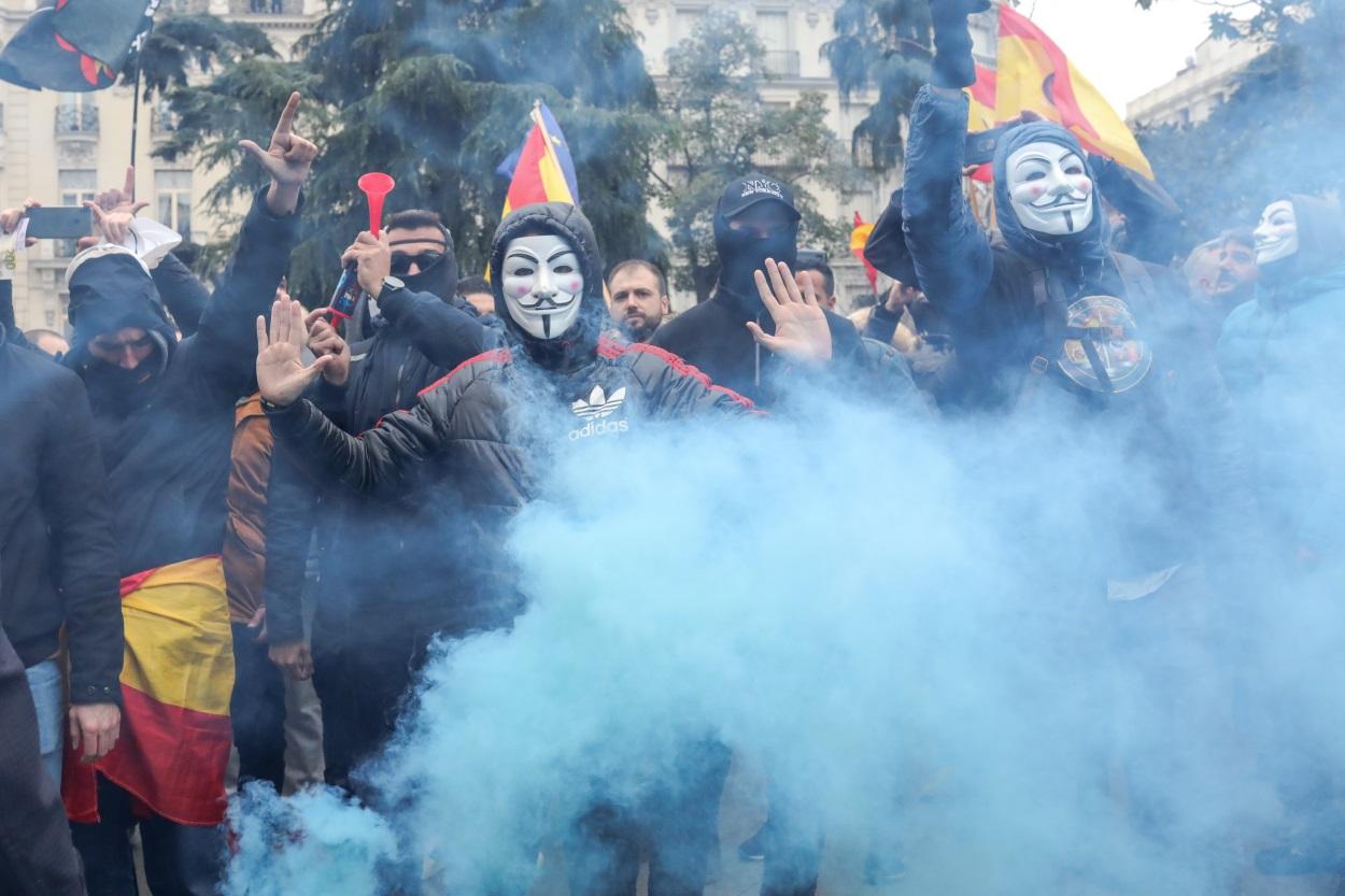Manifestantes con máscaras de Anonymous y banderas de España durante la concentración de Jusapol frente al Congreso