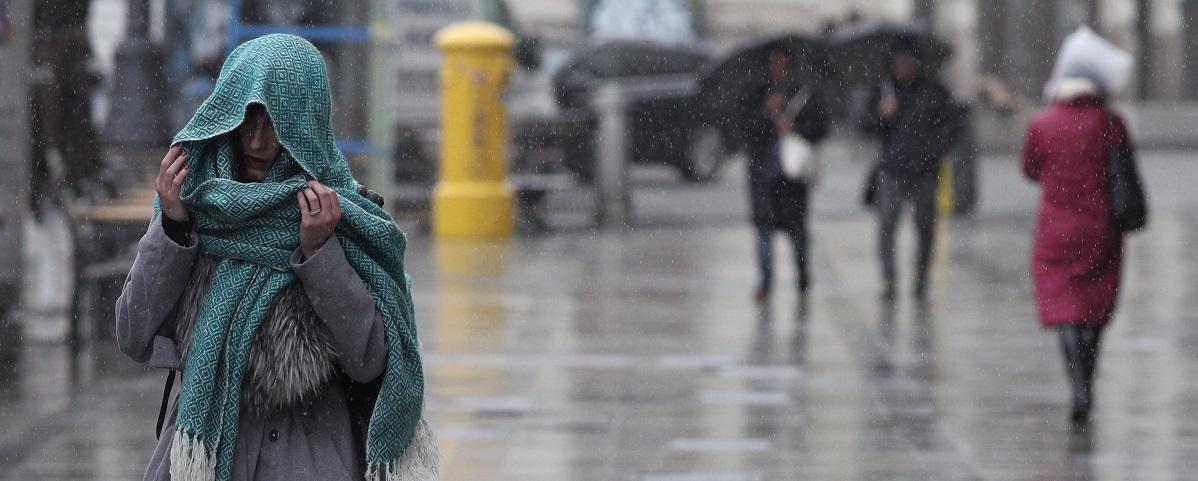 Una mujer se tapa con una bufanda para refugiarse de la lluvia