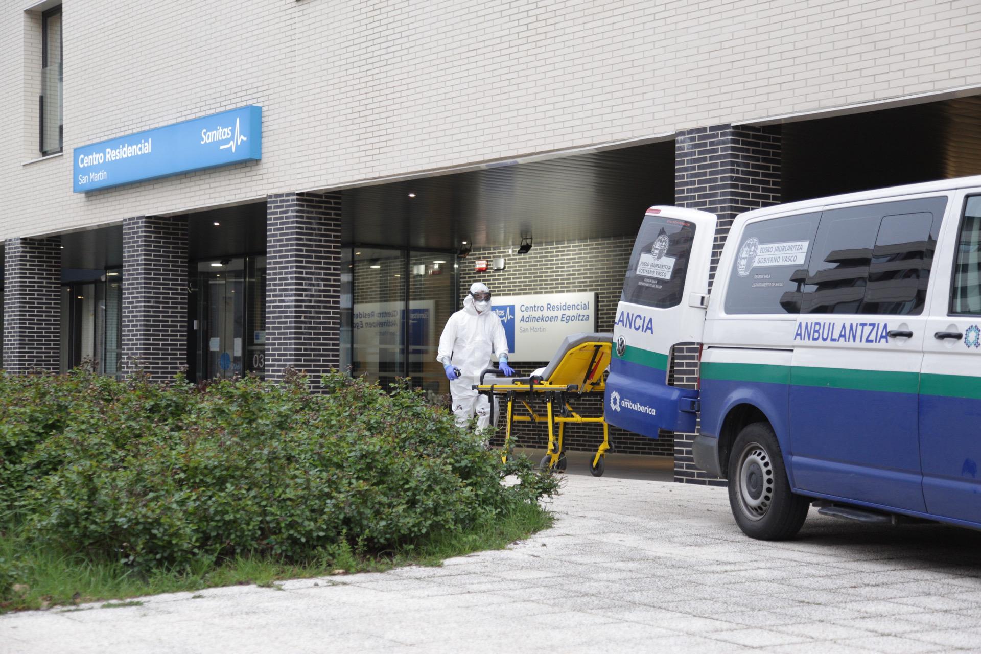 Un sanitario protegido con un traje, guantes y mascarilla, saca una camilla de una ambulancia, en Vitoria/Euskadi (España)