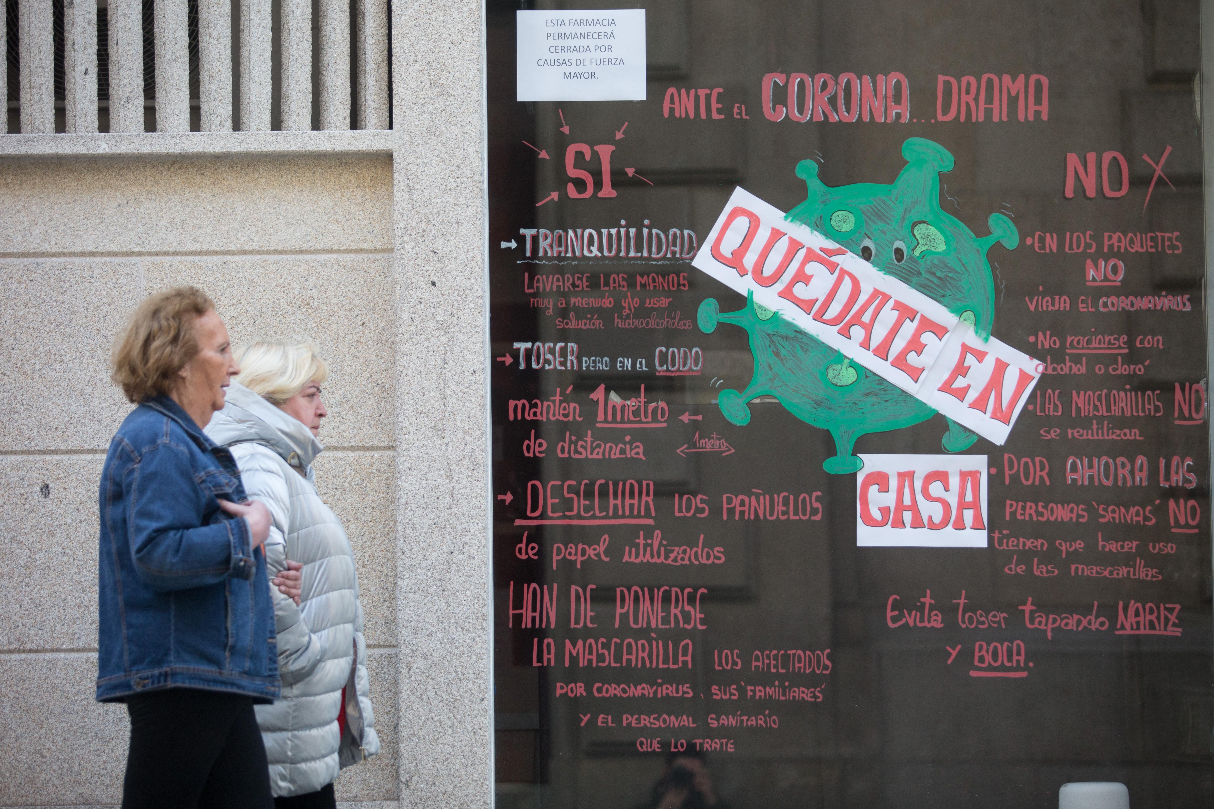 Dos mujeres en Lugo pasean junto a un escaparate con el mensaje "Quédate casa". EP