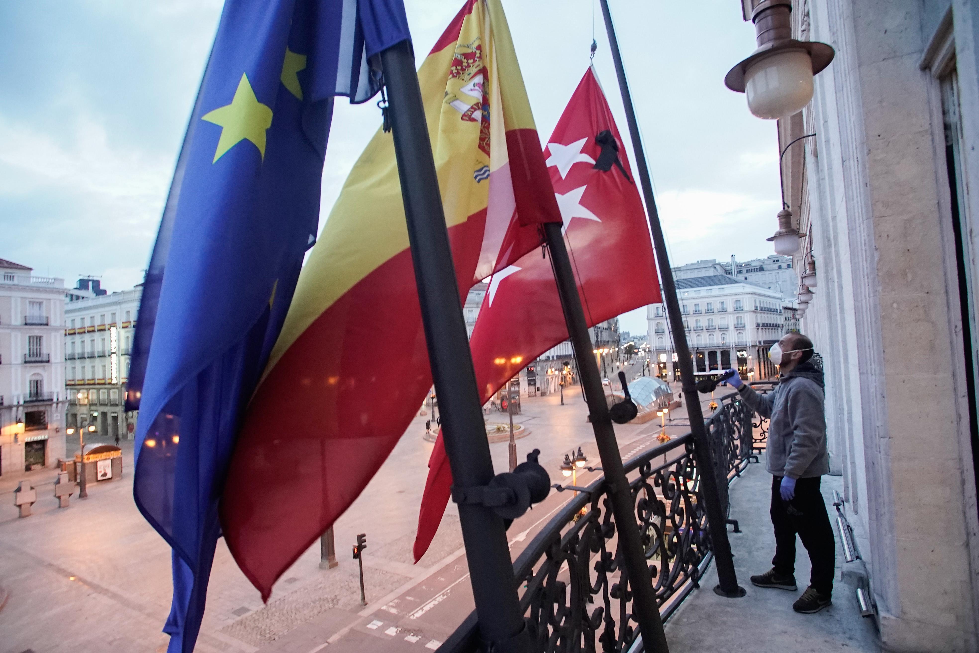 Un operario pone las banderas a media asta en la Puerta del Sol. Comunidad de Madrid.  