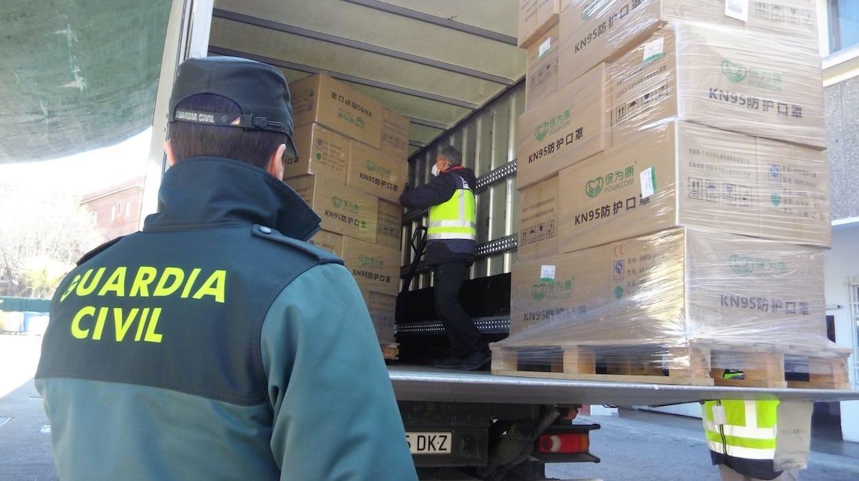 Un agente de la Guardia Civil supervisa la descarga de material sanitario de protección.