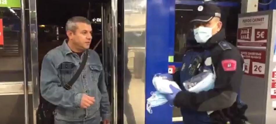 Un policía reparte mascarillas en la entrada del Metro 