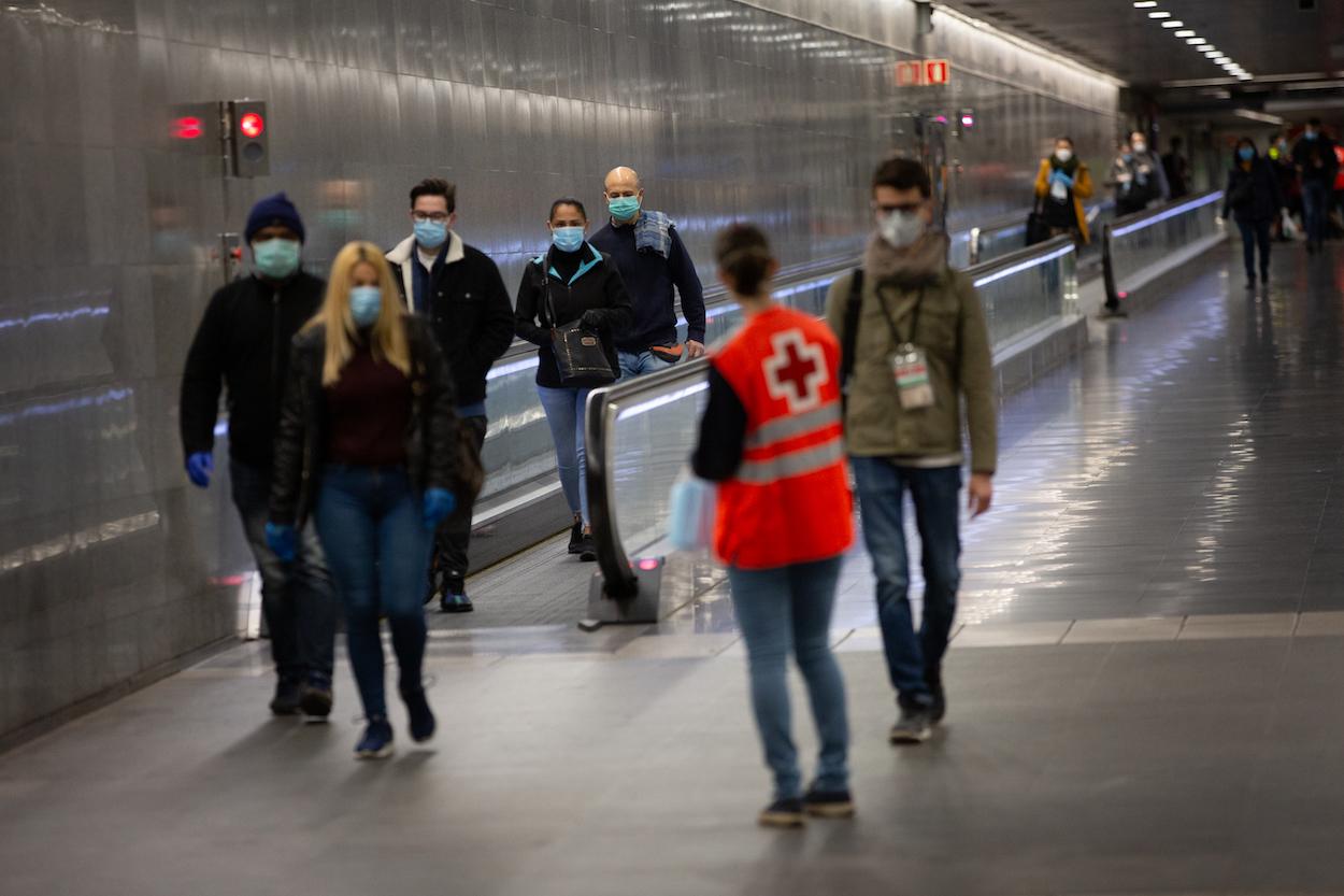 Una voluntaria de Cruz Roja entrega mascarillas a los pasajeros en la estación catalana de Diagonal 