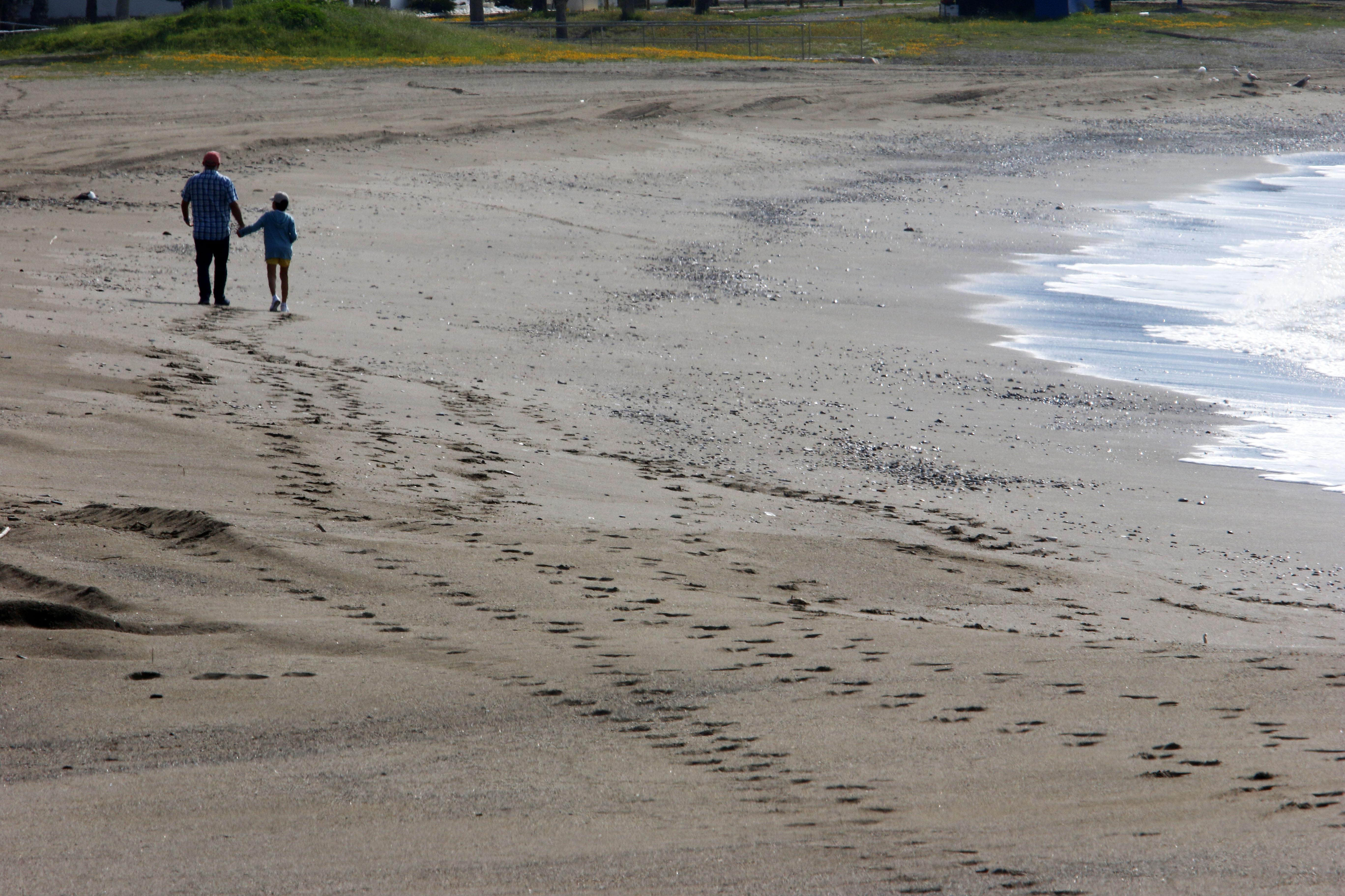 Una mujer con un niño en la playa de La Malagueta el primer día en el que los menores de 14 años pueden salir, en Málaga 