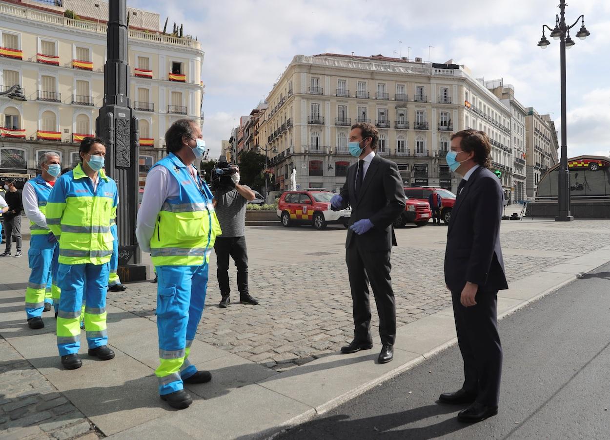 El líder del Partido Popular, Pablo Casado (2d), y el alcalde de Madrid, José Luís Martínez Almeida, conversan con personal sanitario