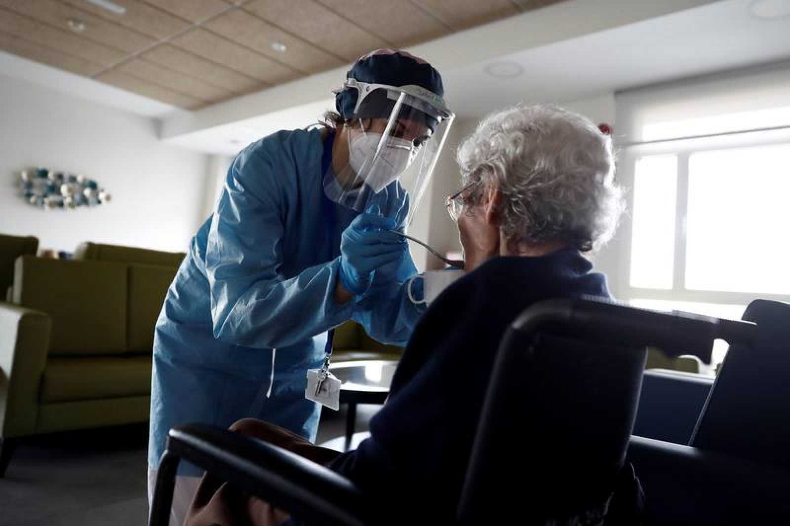 Una sanitaria da de comer a una anciana en una residencia de mayores, con un traje de protección ante el Covid19. RTVE