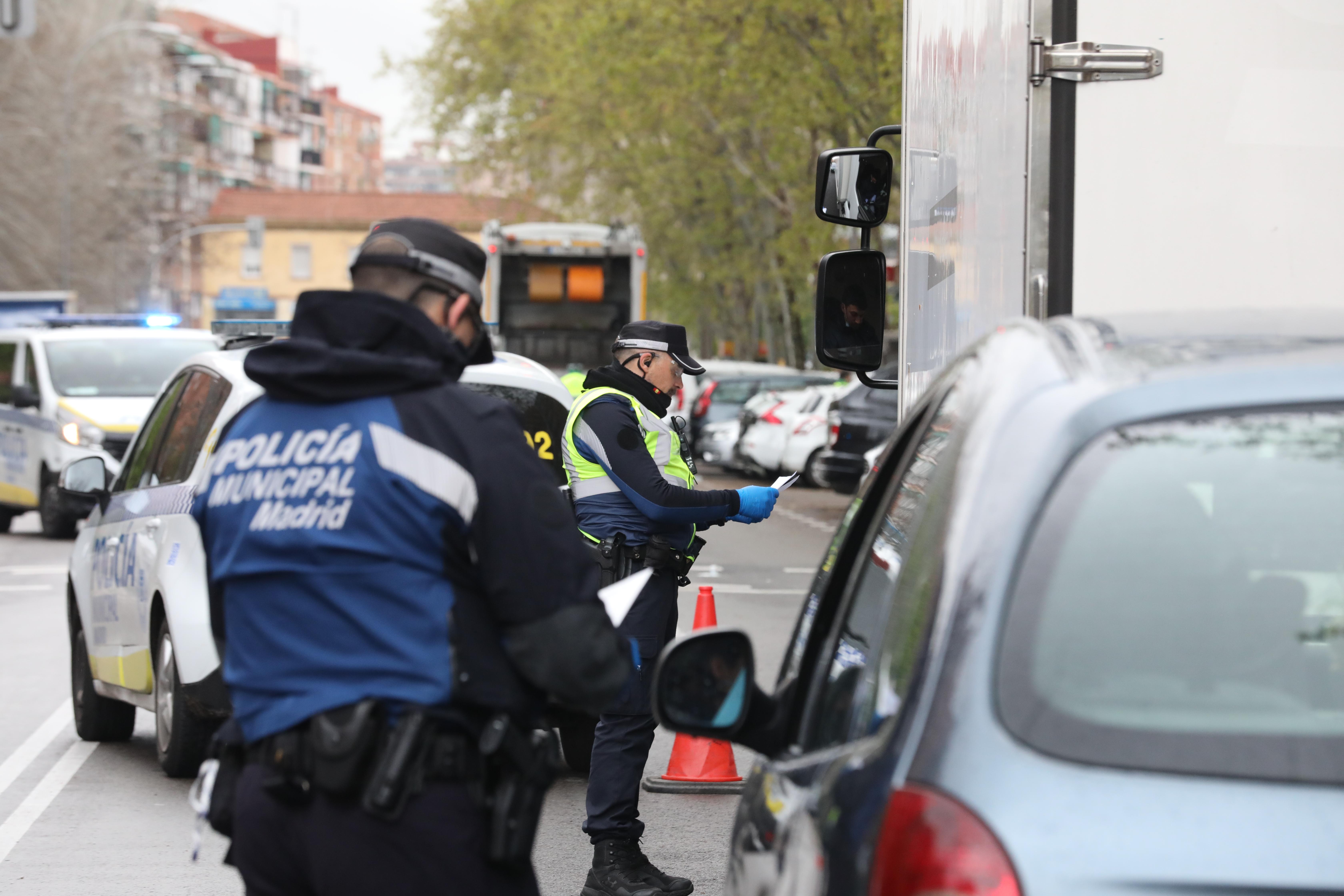 Dos policías municipales dan el alto a dos vehículos, uno de ellos un particular y otro un camión, en un control de policial en el municipio madrileño de Vallecas