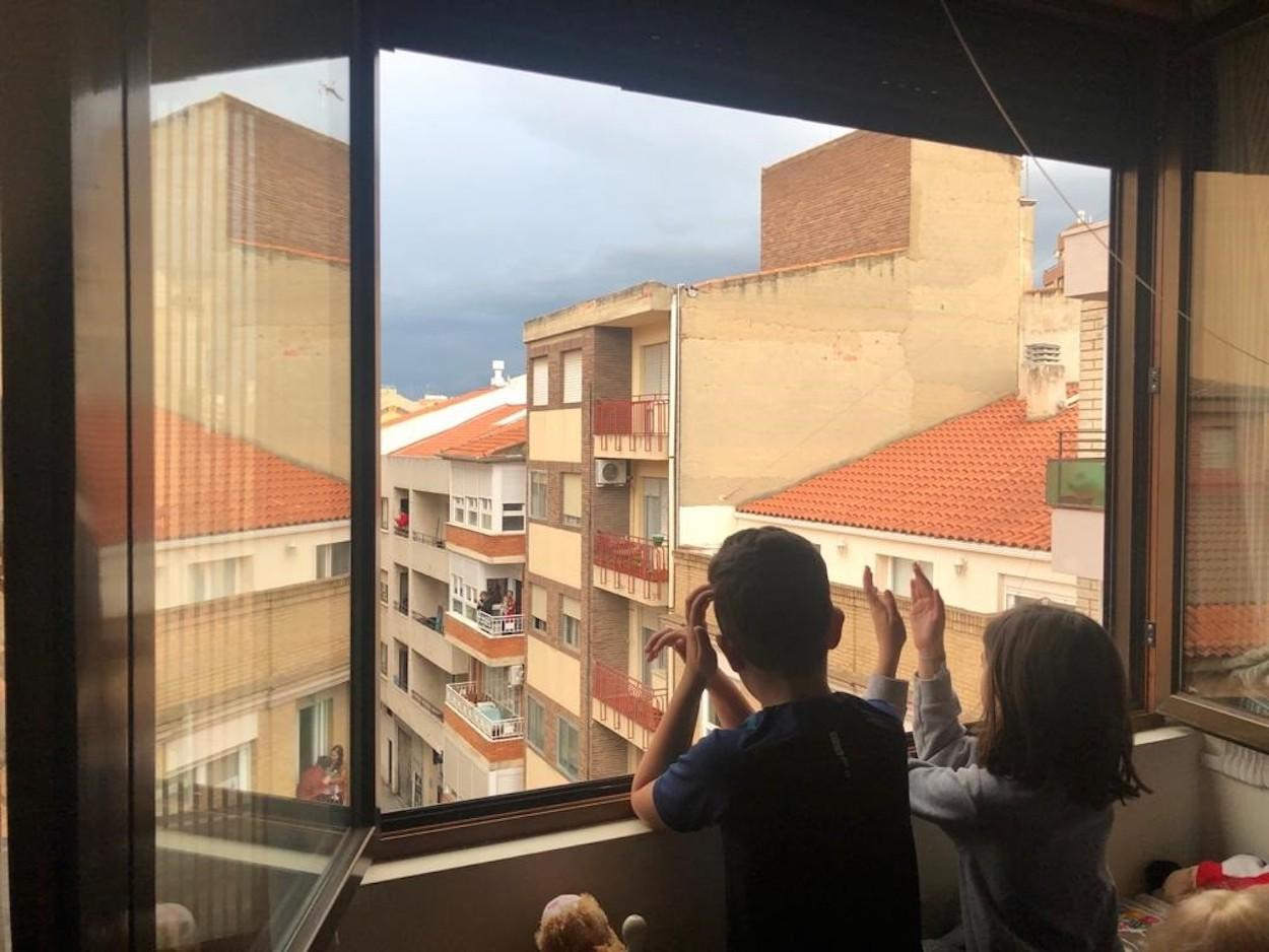 Niños aplaudiendo desde su ventana a las ocho de la tarde.