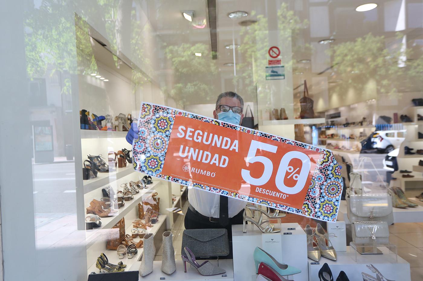 Comerciante colocando el cartel de Rebajas en su establecimiento. EP