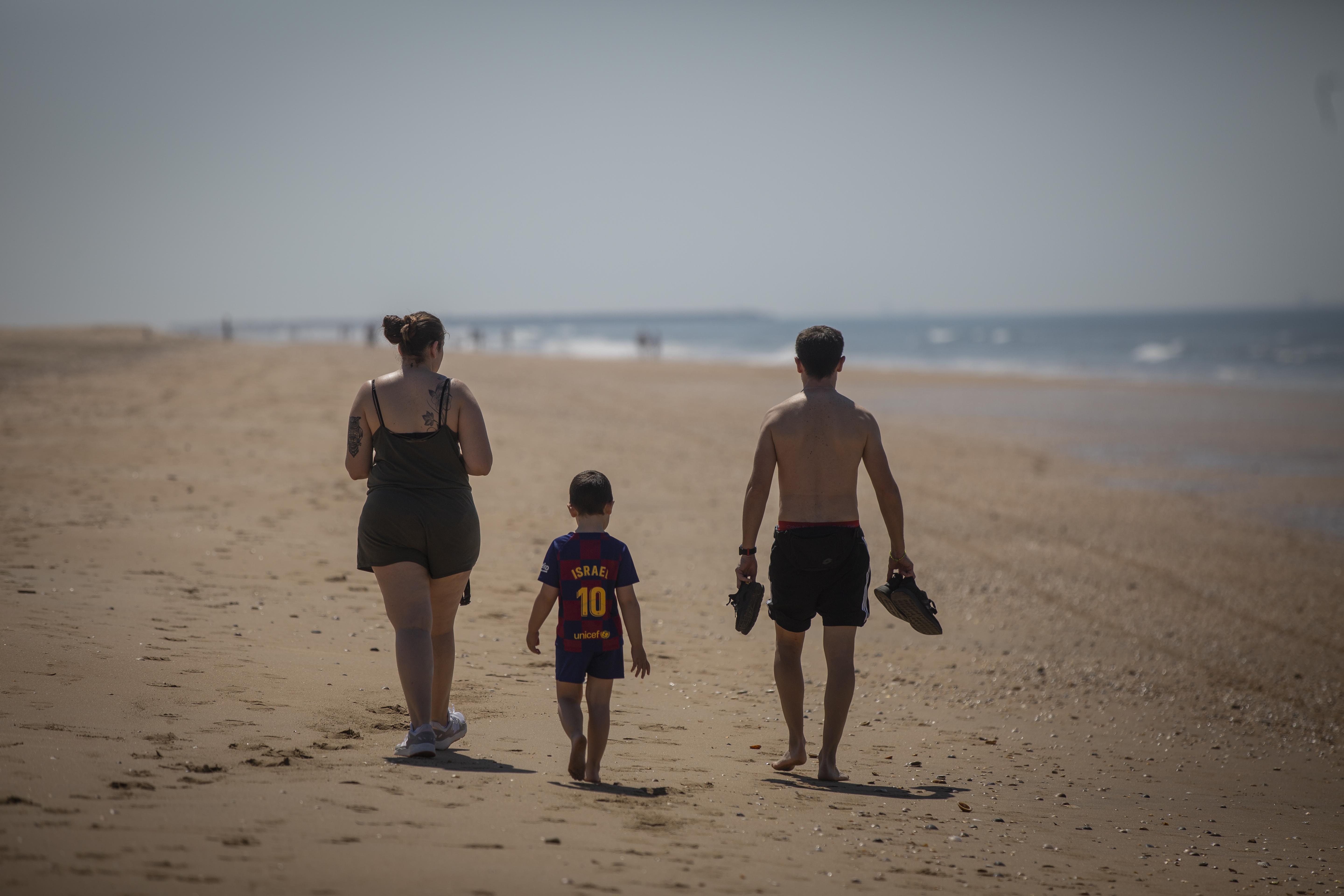 Una familia pasea por la Playa de Punta Umbría, abierta para el paseo y la práctica deportiva como único uso permitido