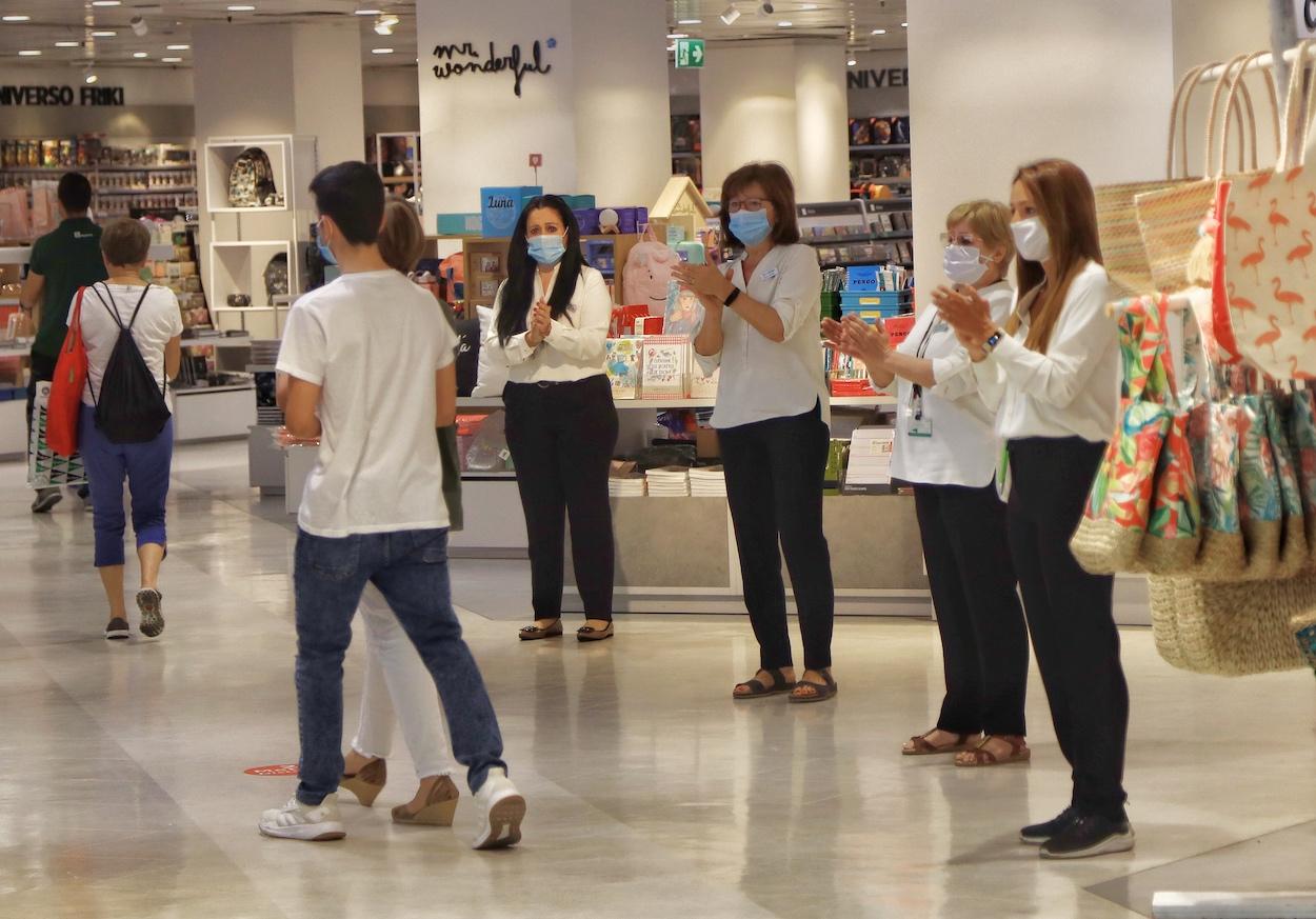 Varias dependientas de un comercio protegidas con mascarilla aplauden respetando la distancia de seguridad en el primer día de la Fase 2 de desescalada