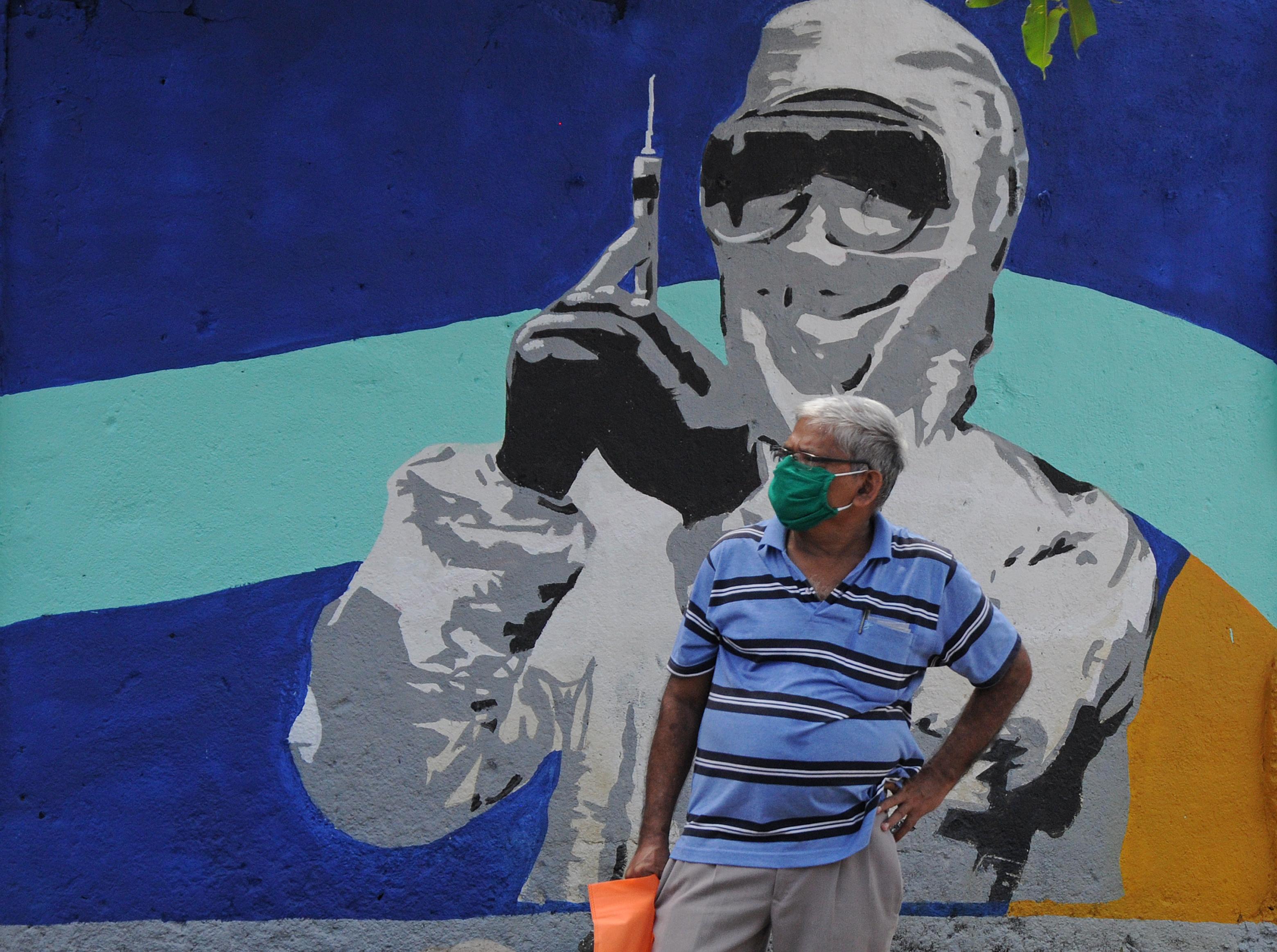 Un hombre con mascarilla delante de un mural en India / EP