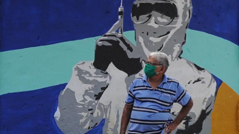 Un hombre con mascarilla delante de un mural en India / EP