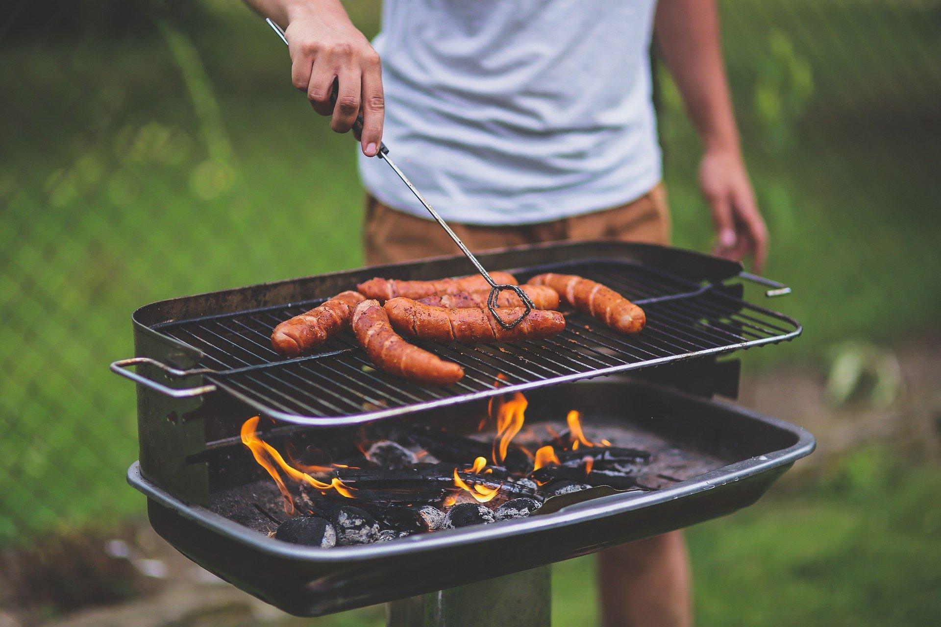 Un hombre cocina unas salchichas en una barbacoa / Pixabay