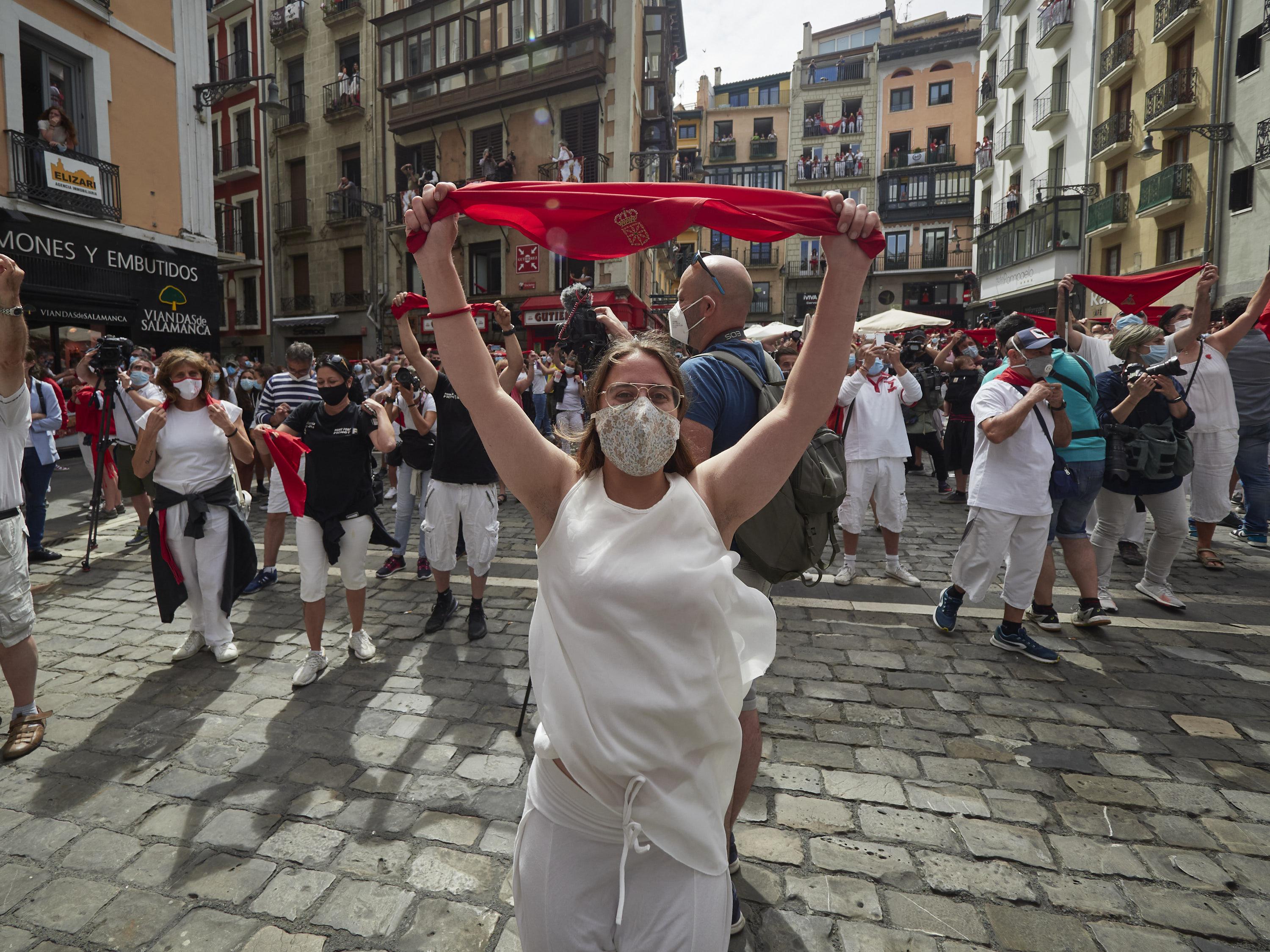  Varias personas alzan un pañuelo rojo en las inmediaciones de la Plaza del Consistorio en el momento en el que de celebrarse los Sanfermines 2020 hubiera tenido lugar el famoso chupinazo