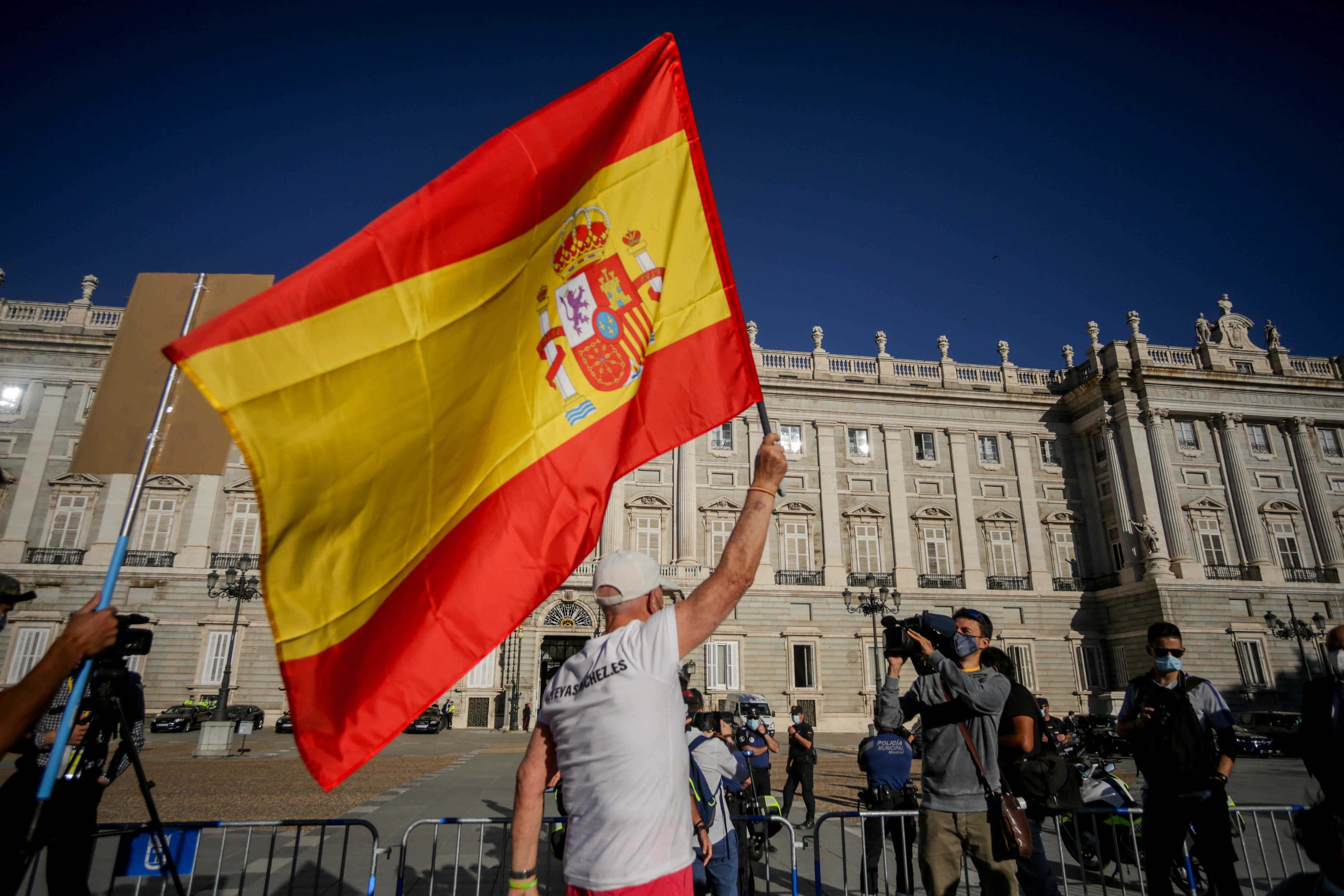 Un hombre ondea una bandera de España en el exterior del Palacio Real antes del inicio de la ceremonia de Estado para homenajear a las víctimas de la pandemia de Covid-19, celebrada en el Palacio Real de Madrid (España), a 16 de julio de 2020.
