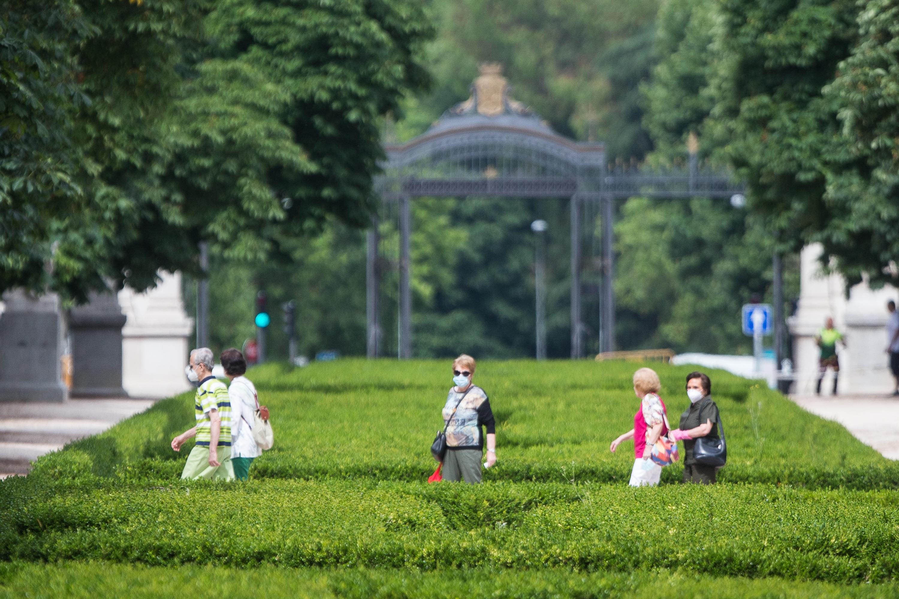 Varias personas pasean protegidas con mascarillas por el Parque de El Retiro 