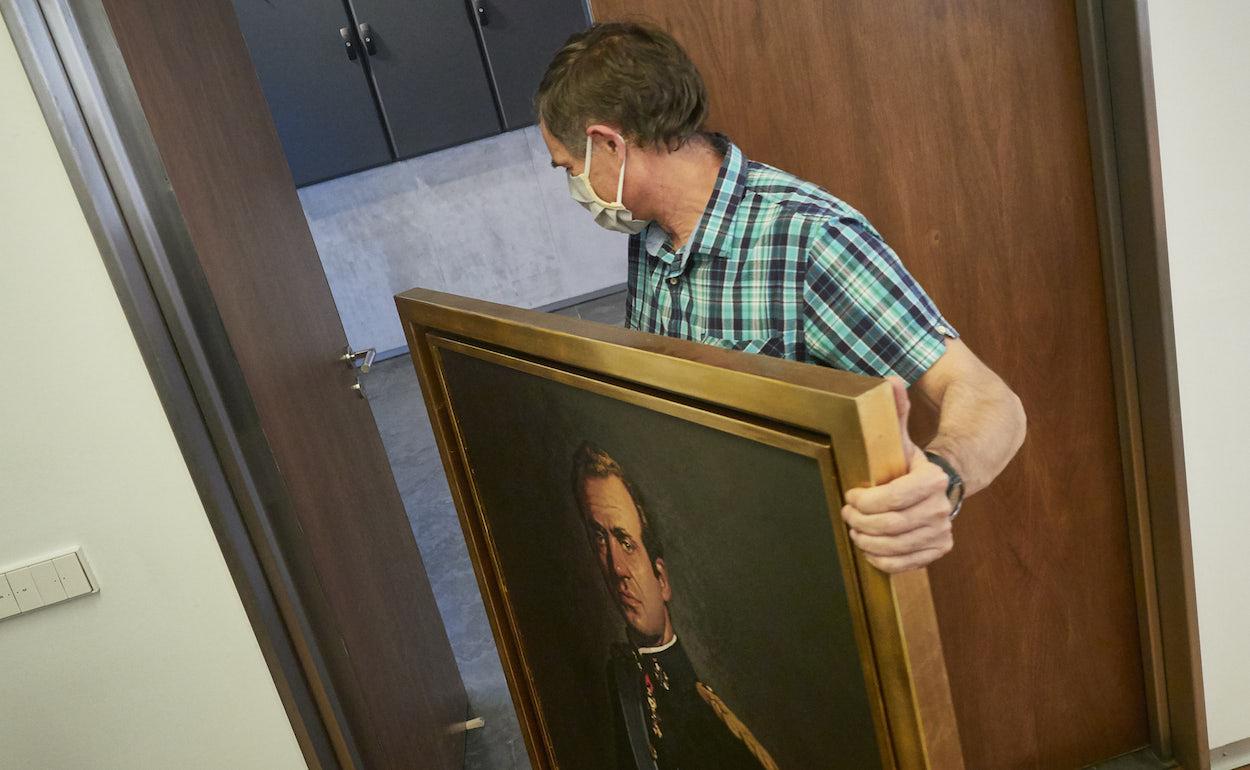 Un operario retira, en julio pasado, el retrato del rey emérito de la Sala de Gobierno del Parlamento de Navarra. EDUARDO SANZ/EP