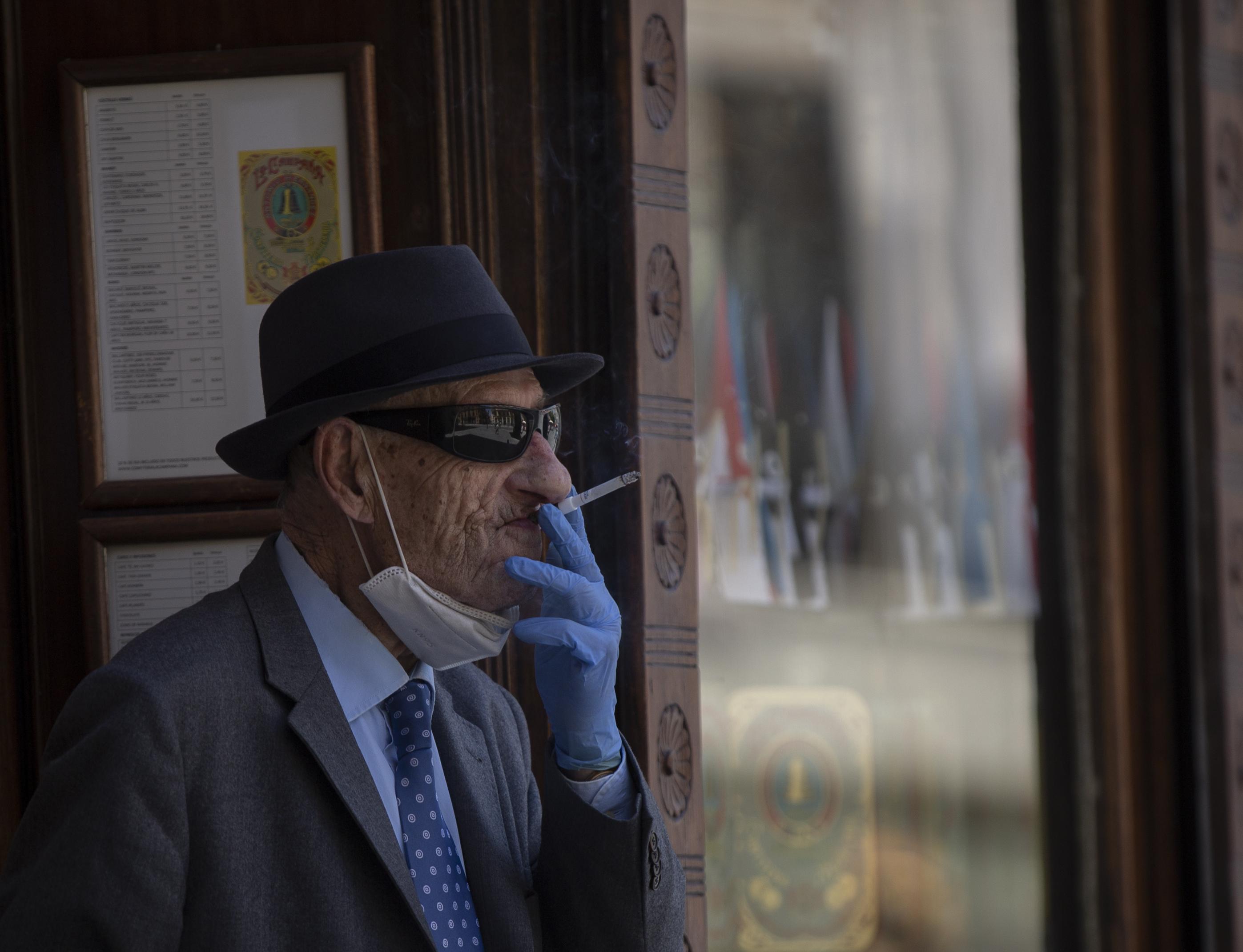 Un hombre con mascarilla y guantes fumando un cigarro / EP