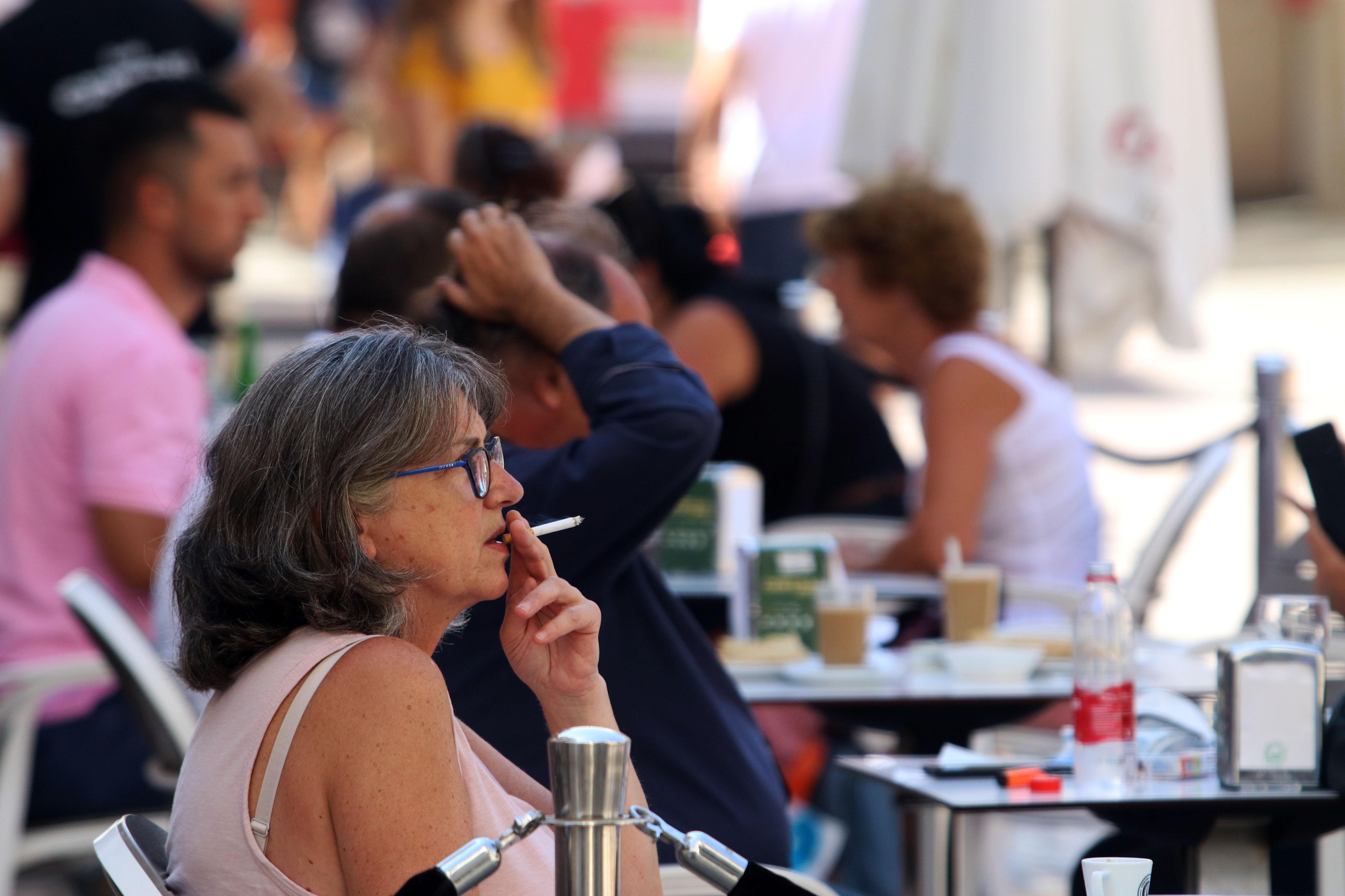 Personas fumando en terrazas y vías públicas durante el día en el que se ha decretado la prohibición de fumar en espacios públicos si no se respeta la distancia de seguridad establecida. EP