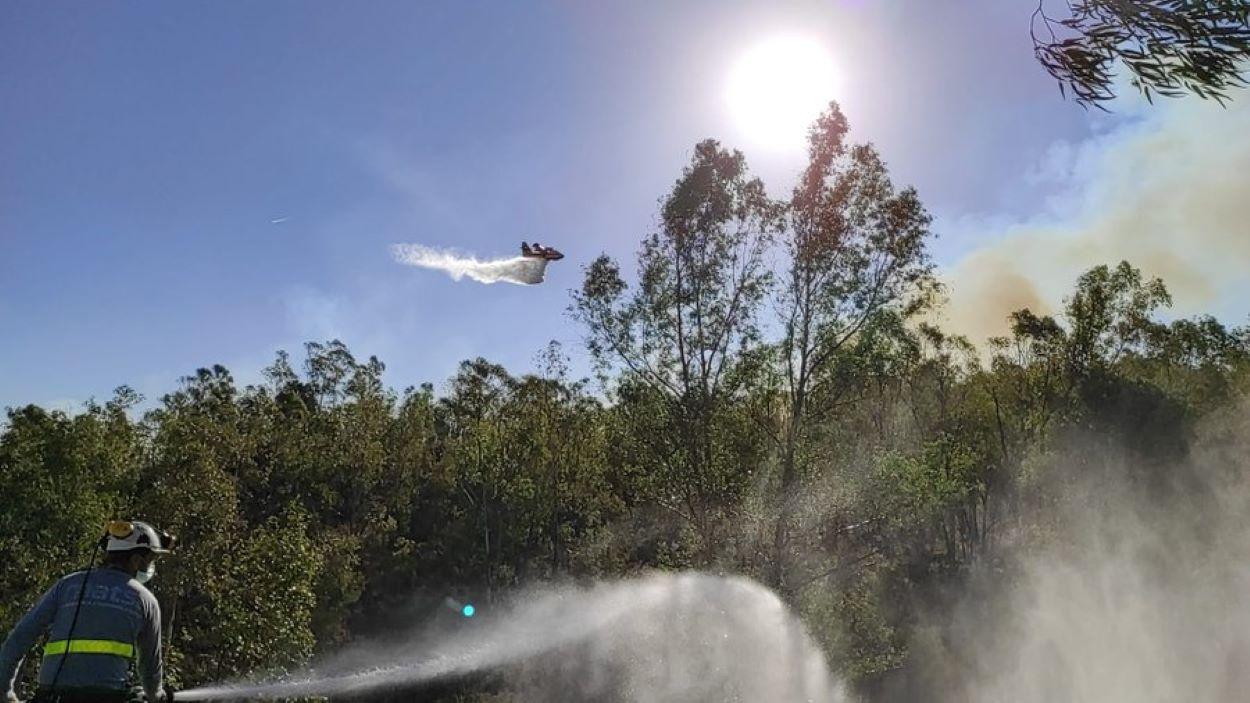 Un avión descarga agua sobre el bosque incendiado en Almonaster la Real (Huelva).