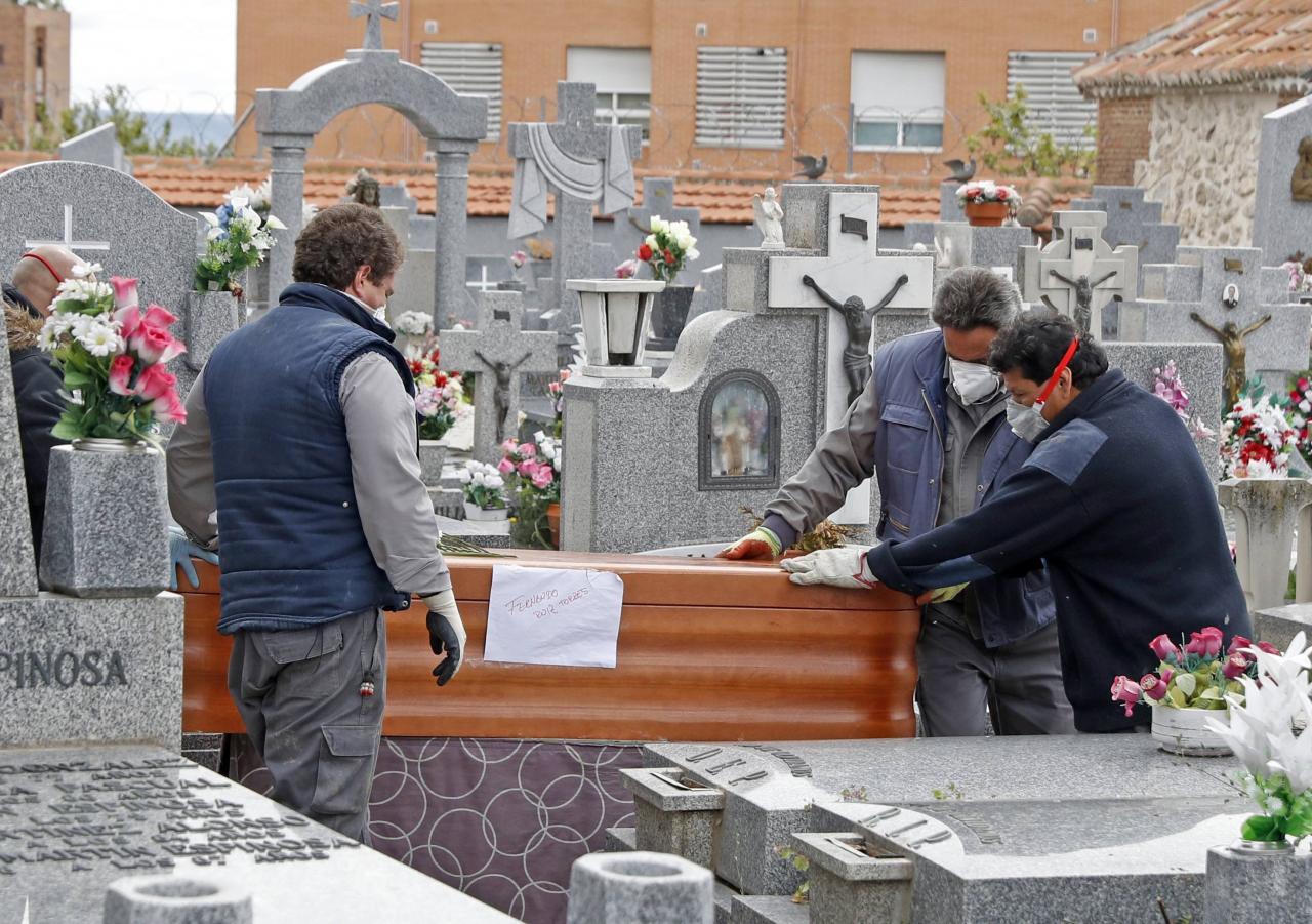 Unos operarios de una funeraria enterrando a un fallecido por covid-19.