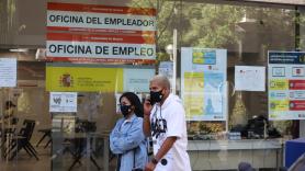 Una pareja con mascarilla pasa por una oficina de empleo de Madrid (España).