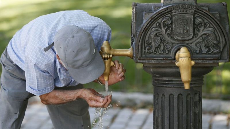 Un hombre bebe en una fuente del parque del Retiro en Madrid, para combatir la ola de calor en la ciudad. EFE/Archivo