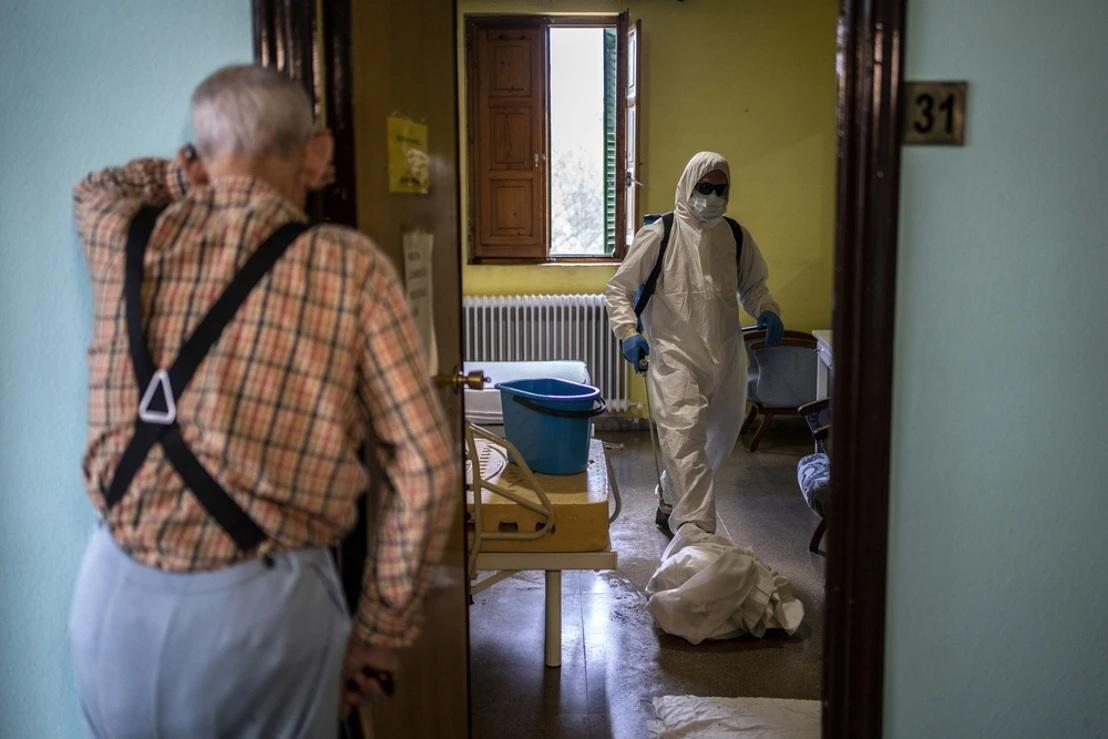  Un anciano contempla en una residencia la actuación del personal sanitario. Imagen de archivo