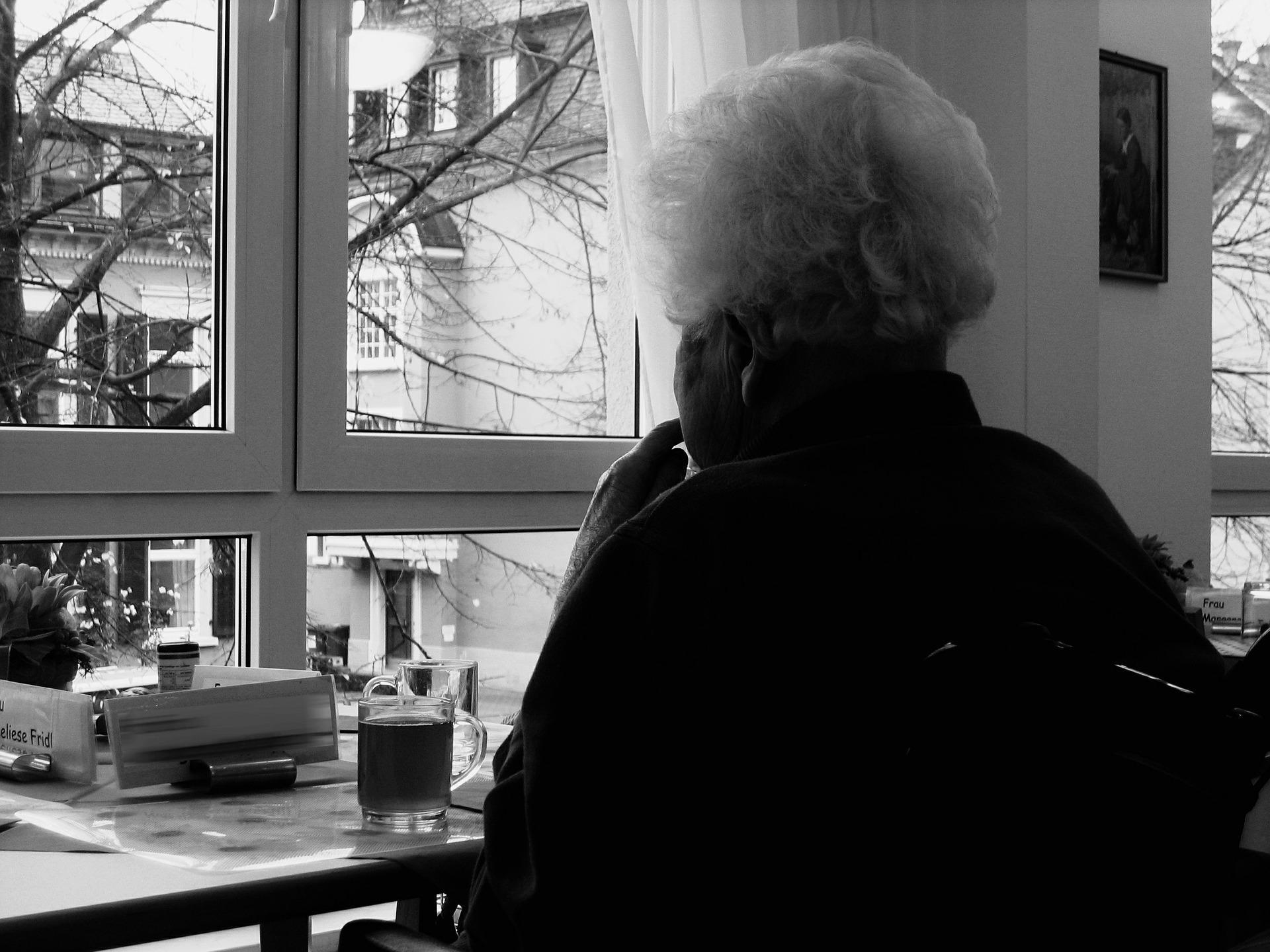 Una señora mayor mirando por la ventana. Pixabay