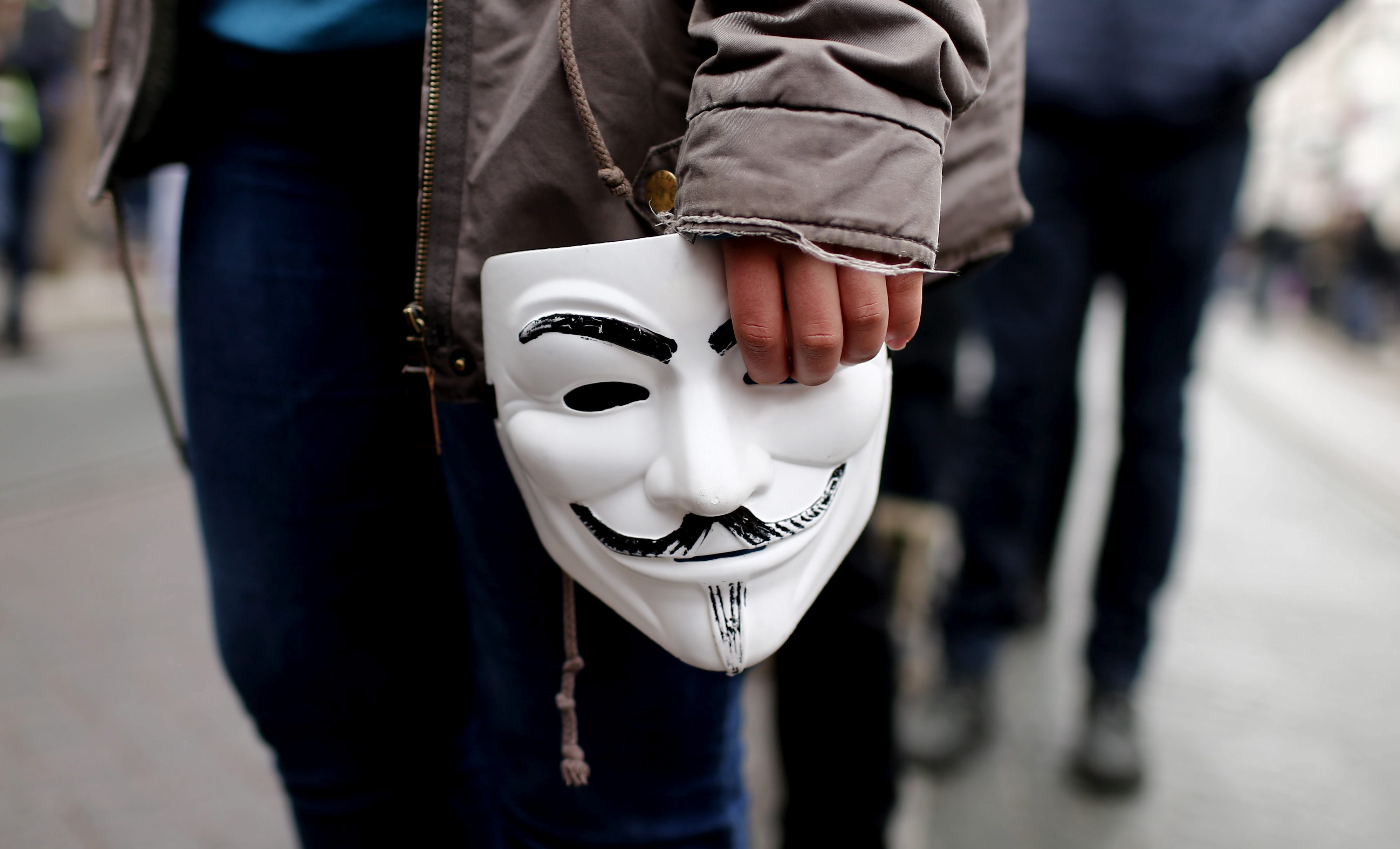 Una persona con la careta que identifica a los miembros de Anonymous